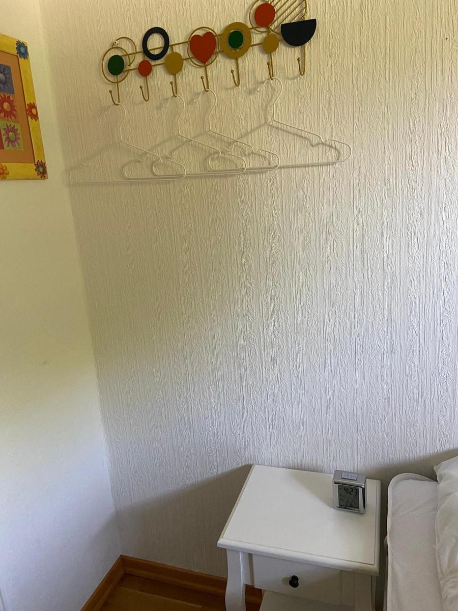 Wand mit Kleiderhaken und Nachttisch neben Bett