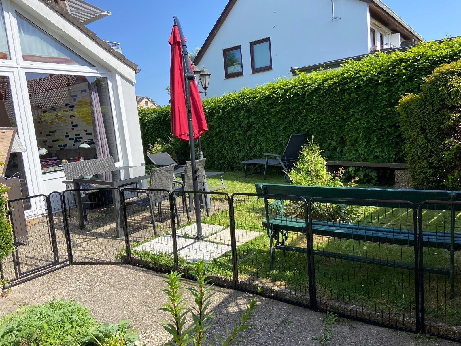 Hinterhof mit Grillplatz, Sitzgelegenheiten und grünem Zaun.