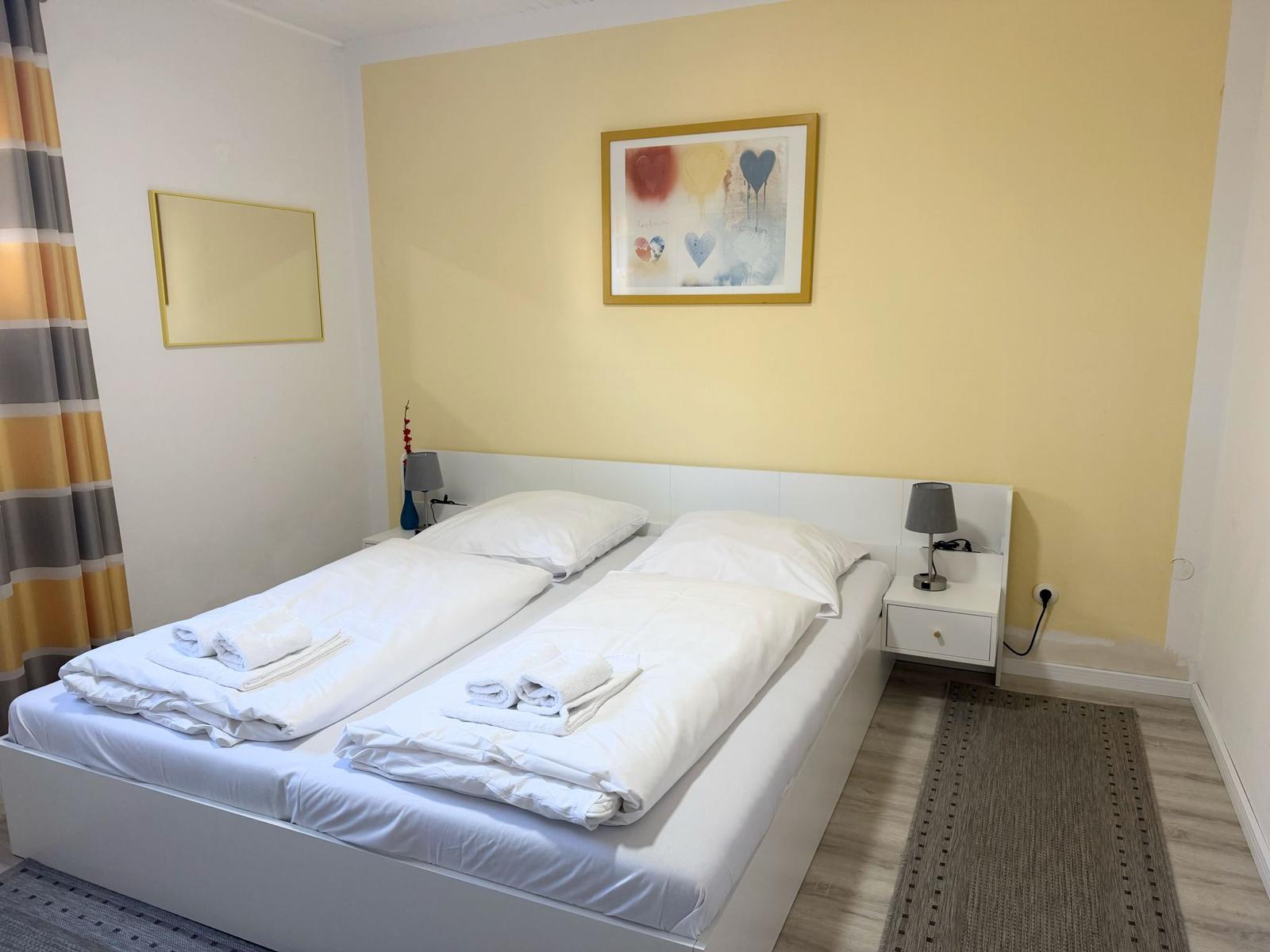 Schlafzimmer mit Doppelbett, zwei Nachttischen und Wandbild.