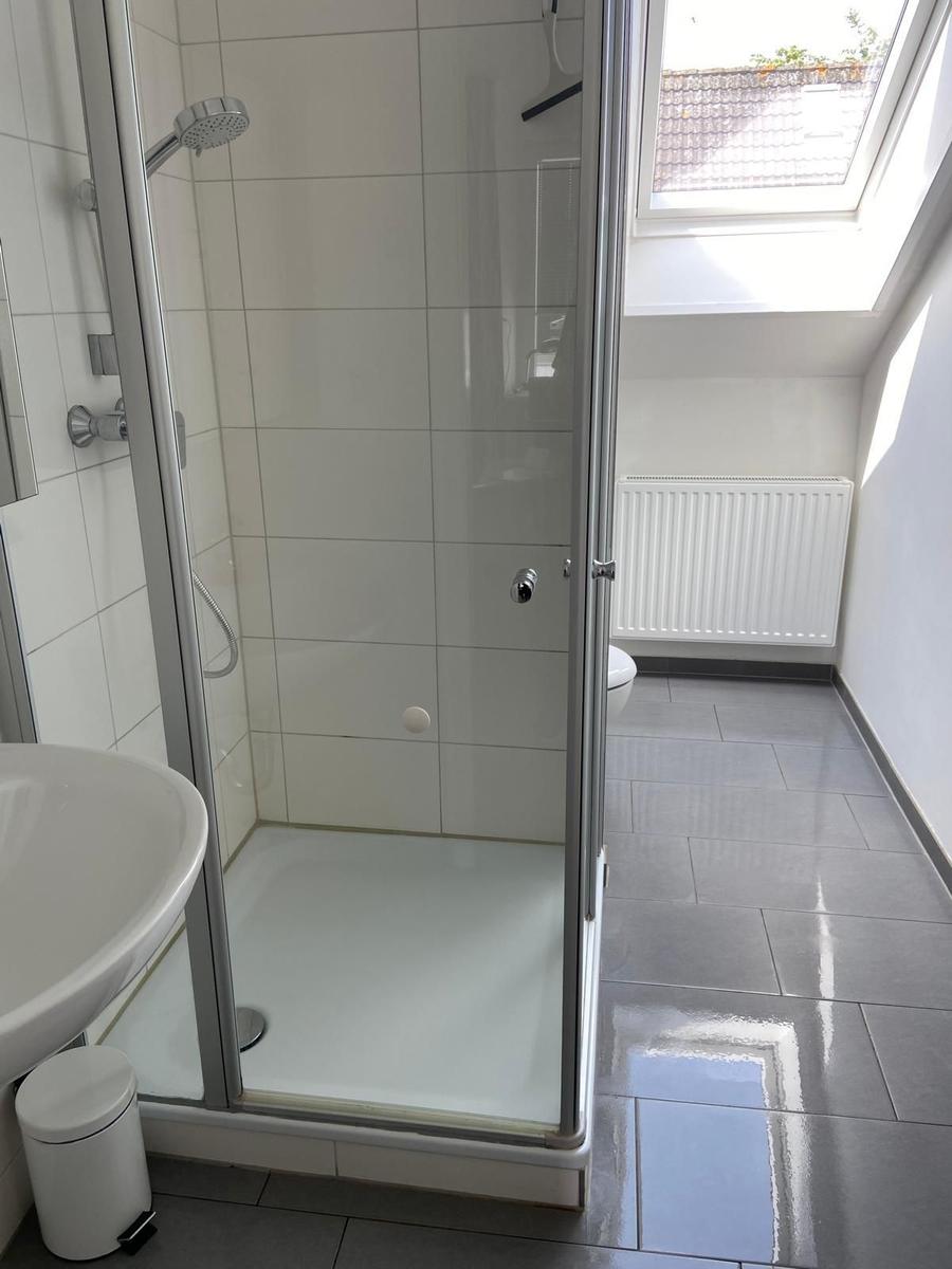 Bad mit Dusche, Waschbecken und Heizkörper unter Dachfenster