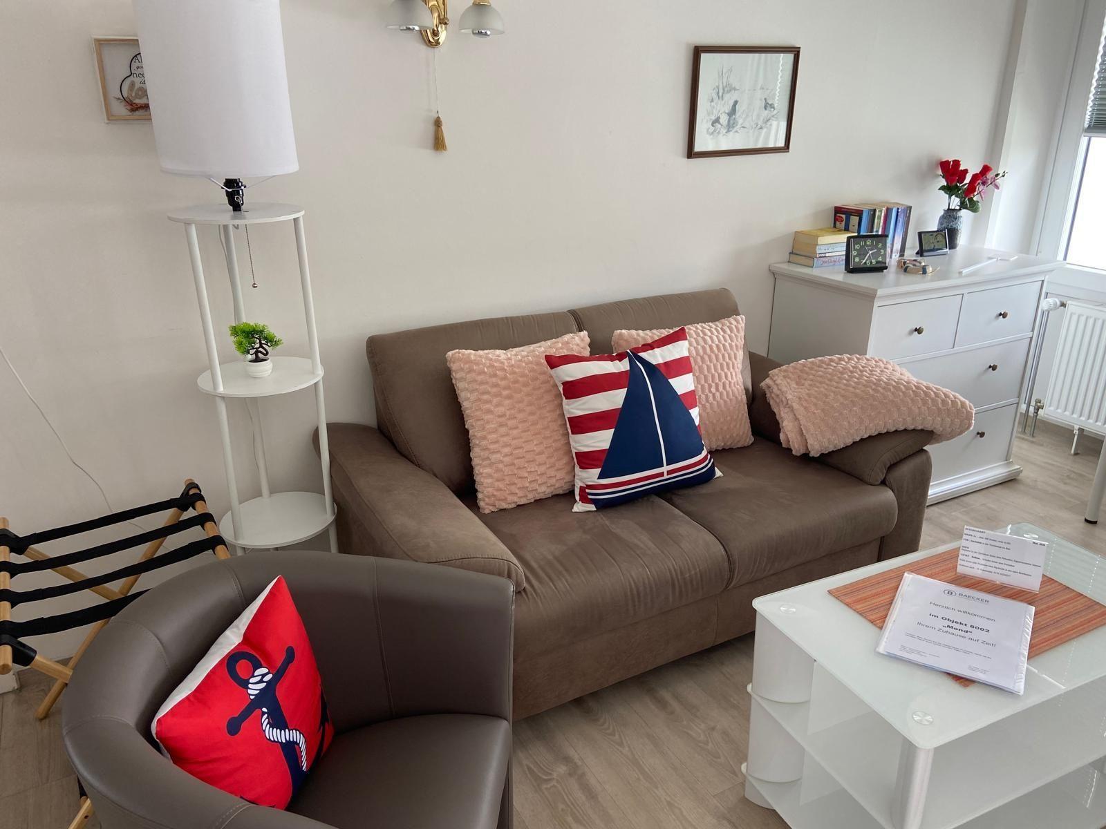 Ein Wohnzimmer mit braunem Sofa, Kissen und weißem Couchtisch.