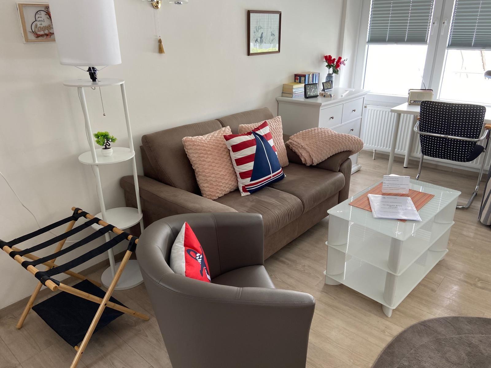 Wohnzimmer mit Sofa, Sessel, Couchtisch und Schreibtisch