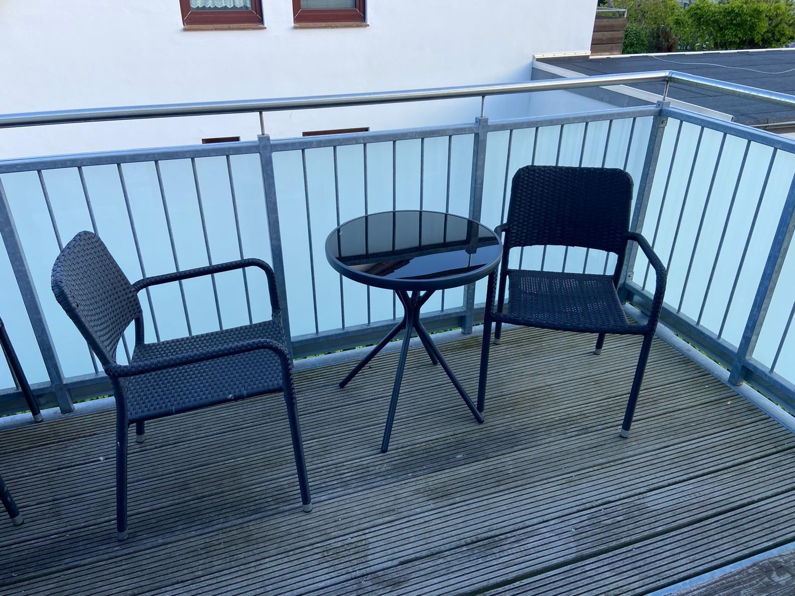 Terrace with two chairs and a round glass table.