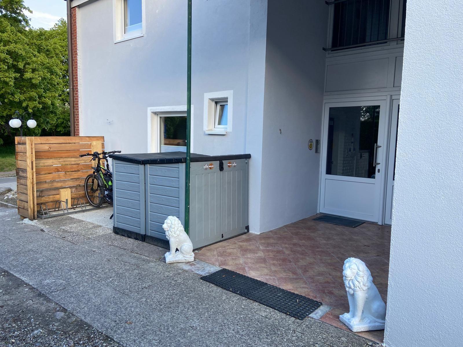 Entrance area with white lion statues, gray storage box, and bicycle.