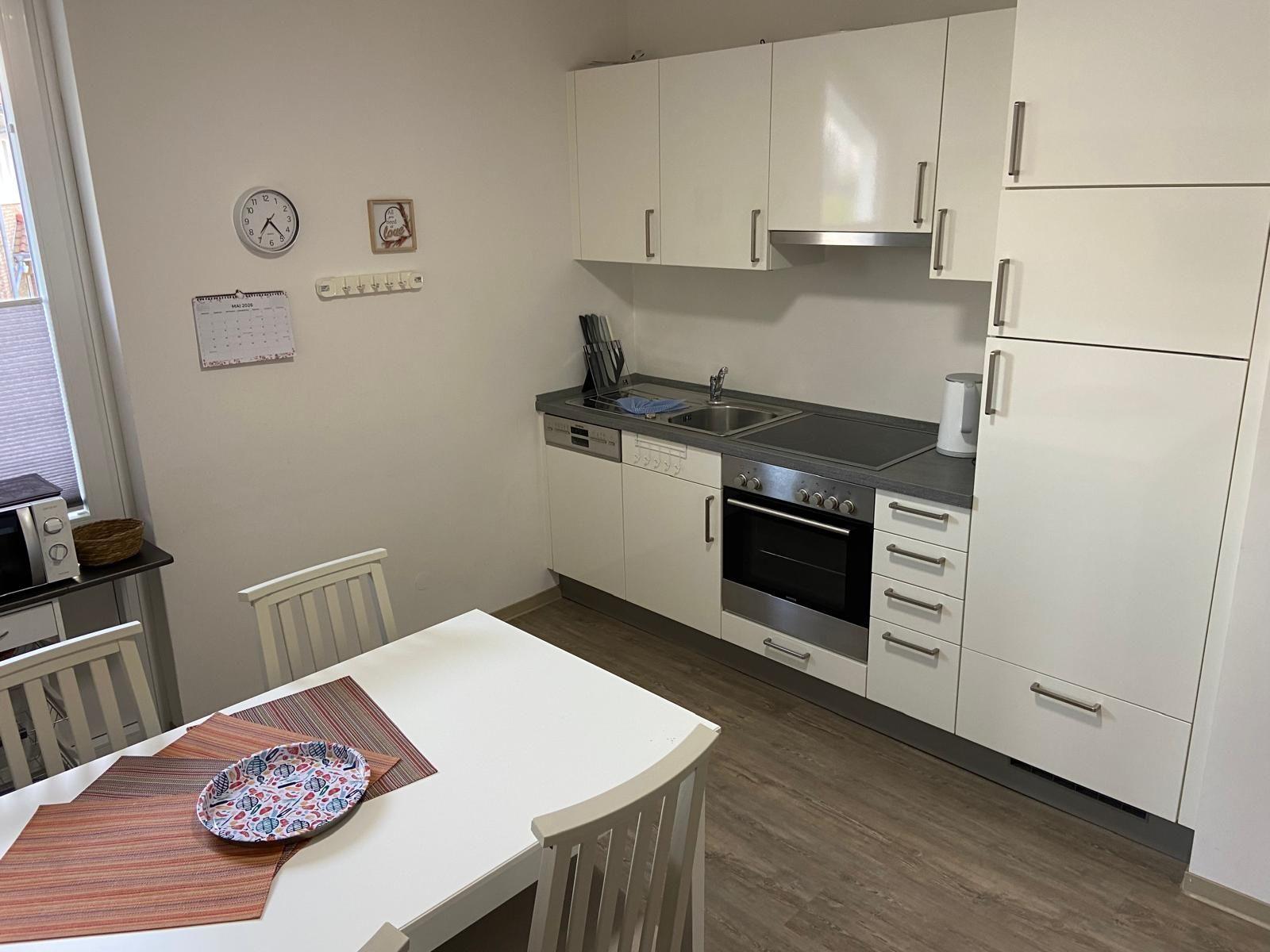 Kitchen with white cabinets, stove, and dining table with chairs.