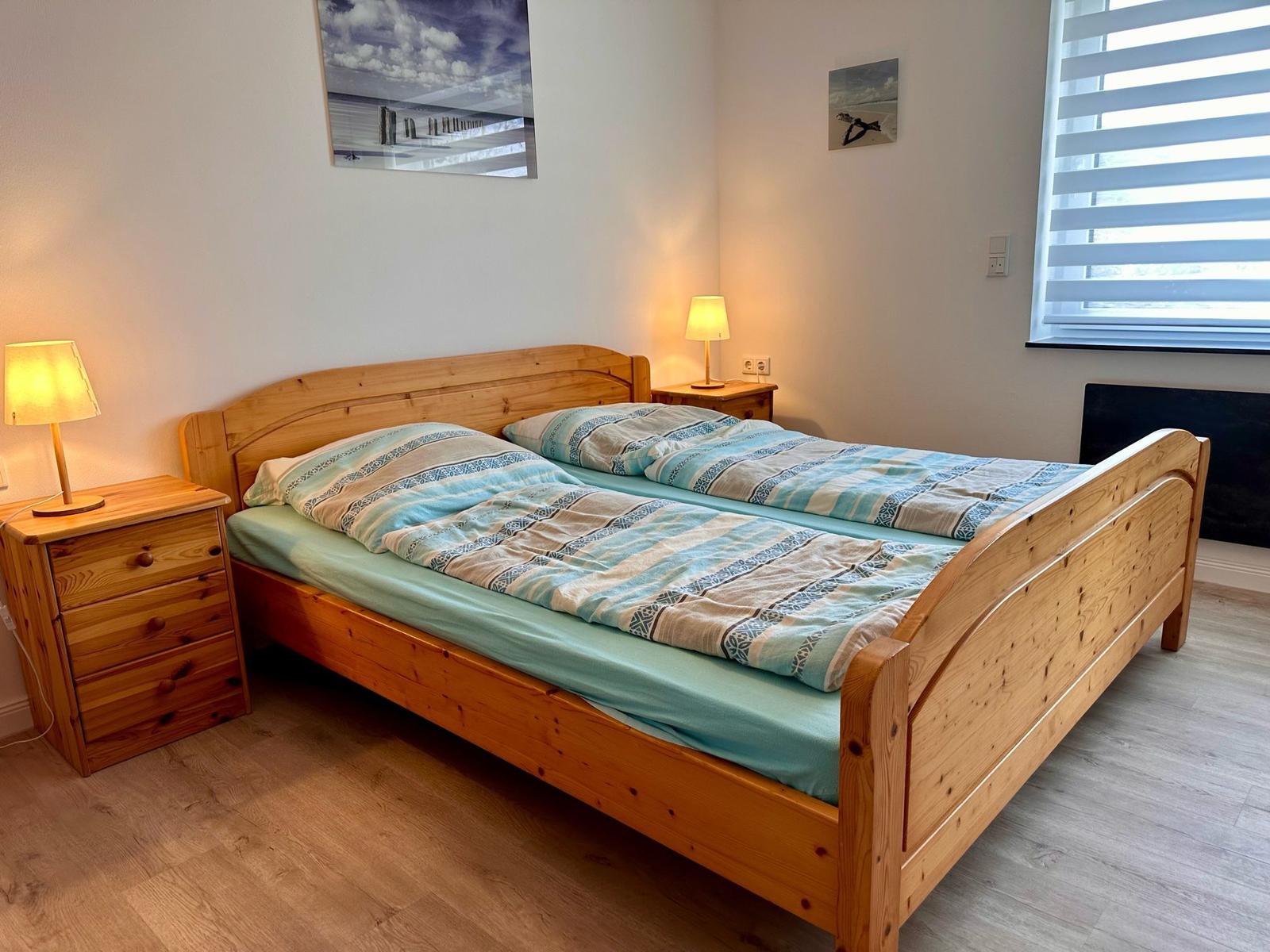 Ein Schlafzimmer mit einem Holzbett, zwei Nachttischen und einem Fenster mit Jalousie.