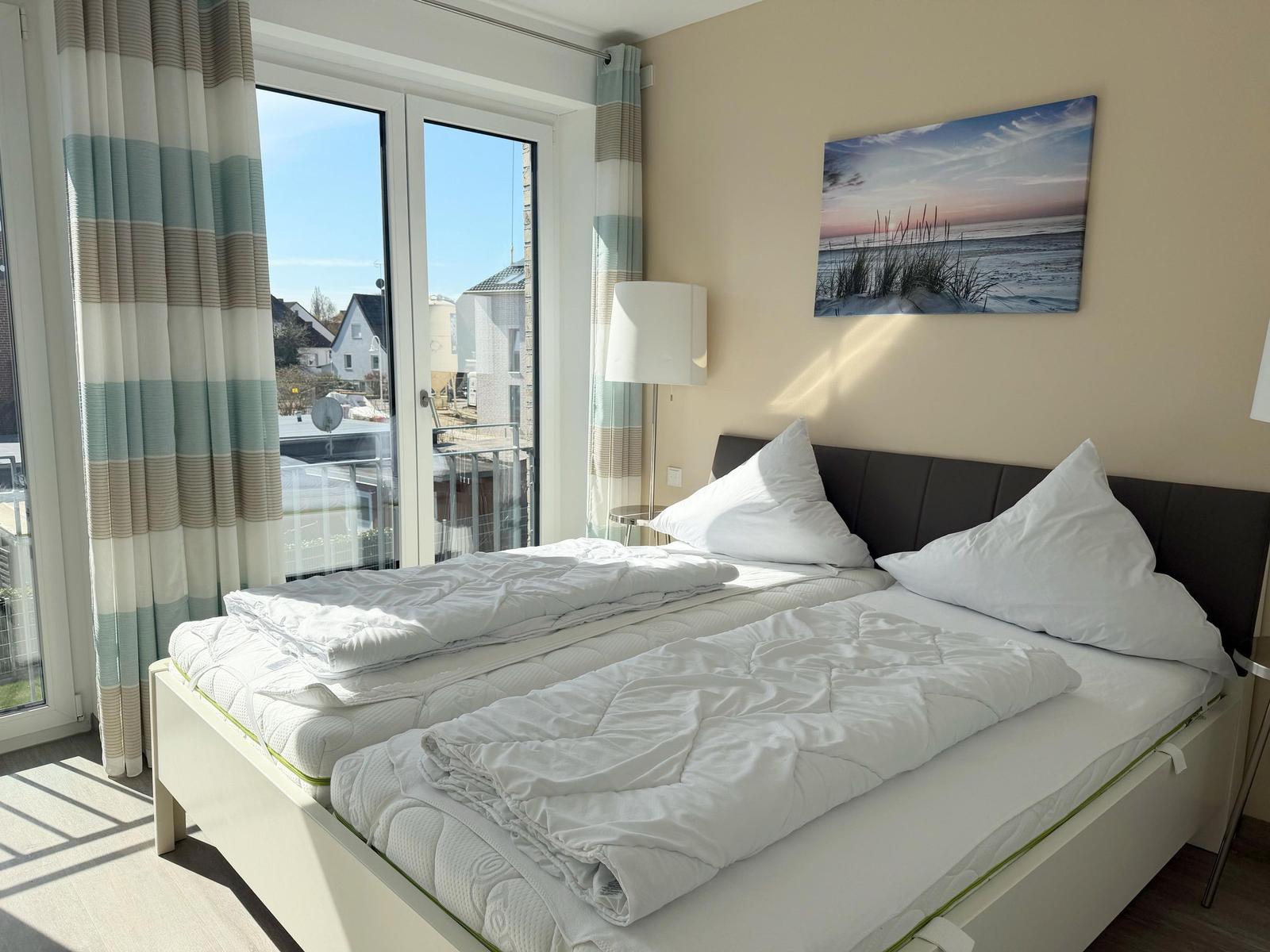 Schlafzimmer mit Doppelbett, Fenster und Wandbild.