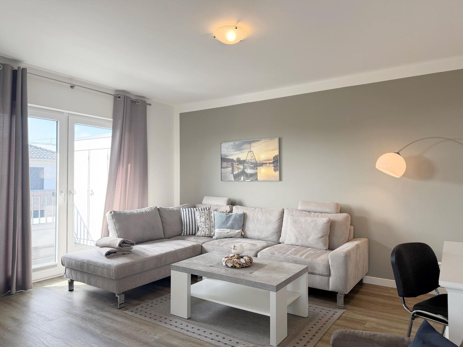 Wohnzimmer mit grauem Sofa, Couchtisch und Fenster zur Terrasse.