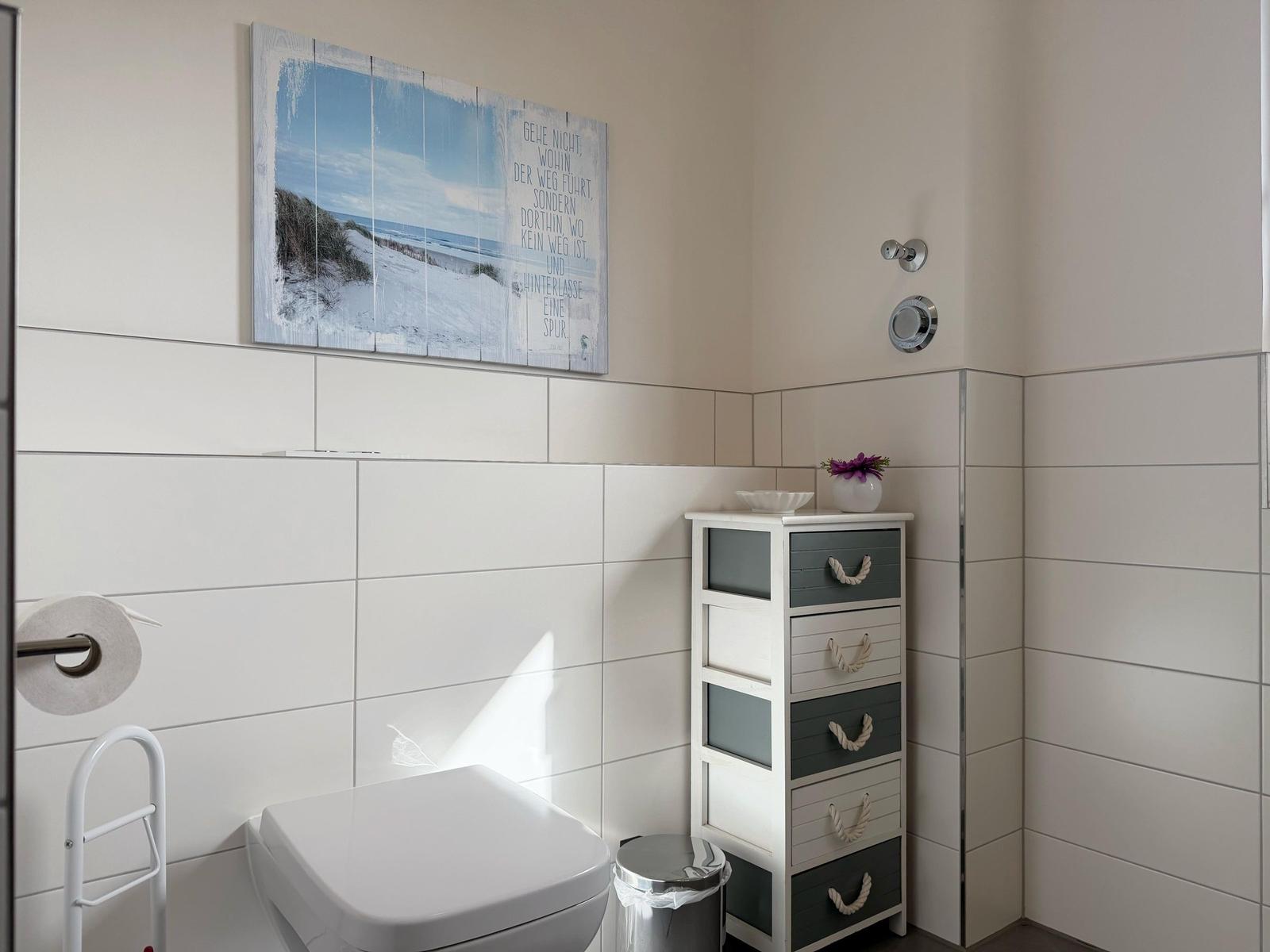 Badezimmer mit Toilette, Kleiderschrank und Wandbild.