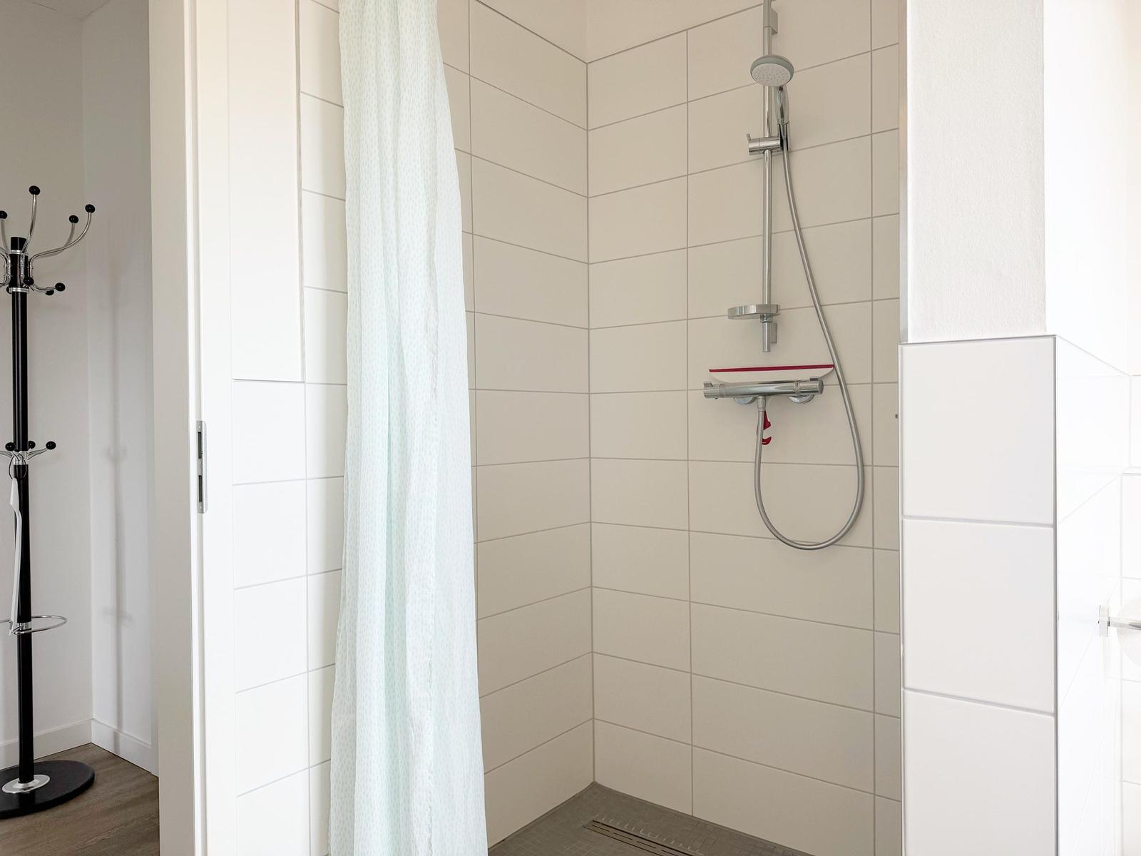 Dusche mit Duschbrause und Duschvorhang in einem Badezimmer