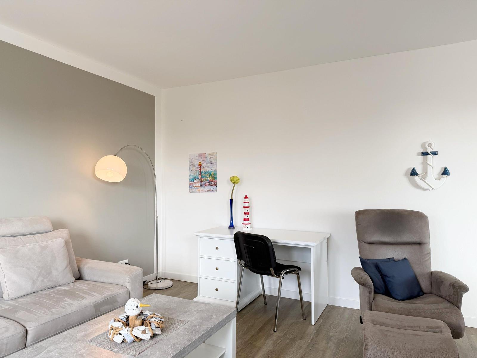 Wohnzimmer mit Sofa, Schreibtisch und Sessel. Wandbild und Ankerdekoration.