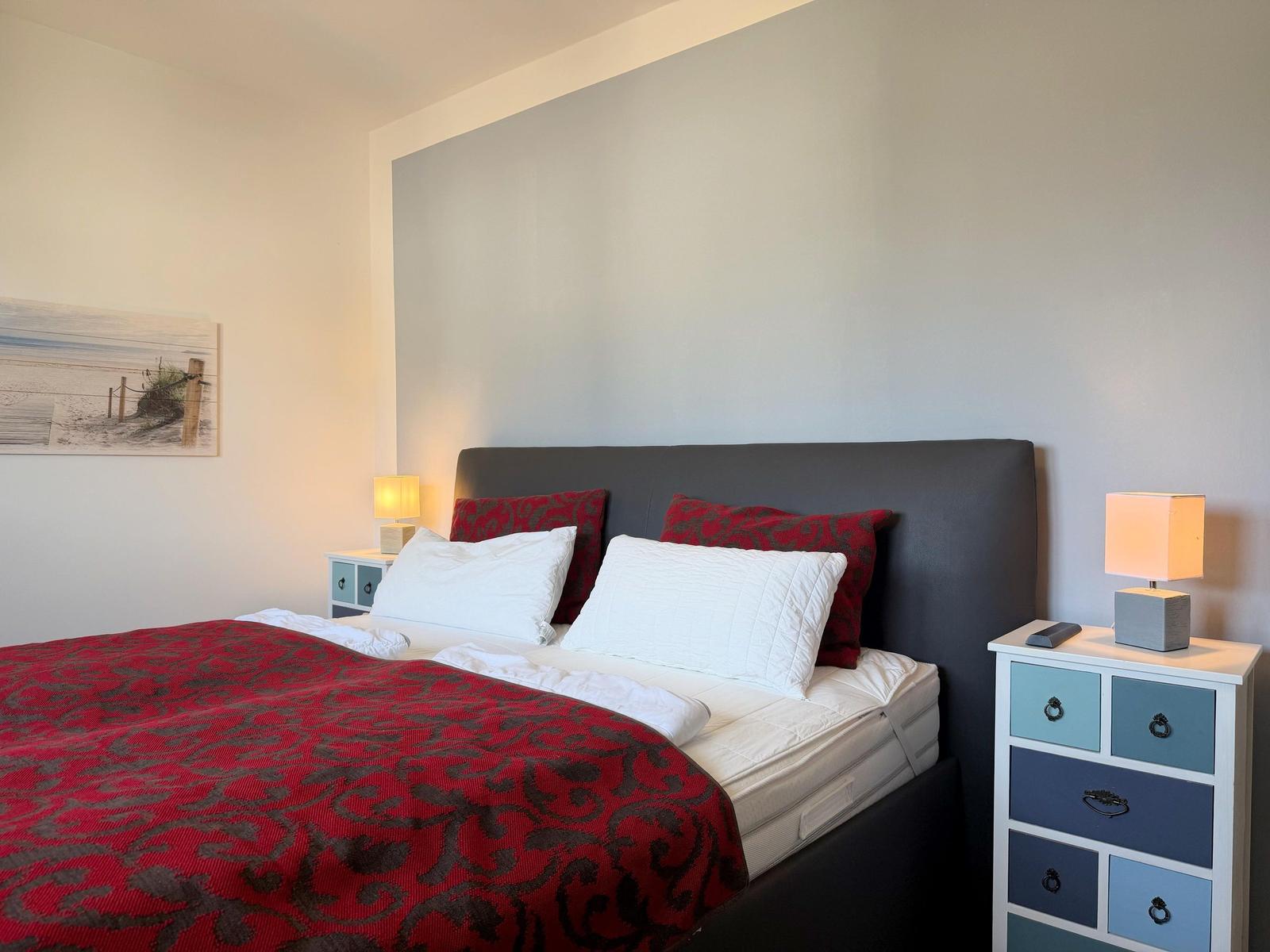 Schlafzimmer mit Bett, Nachttischen und Wandbild