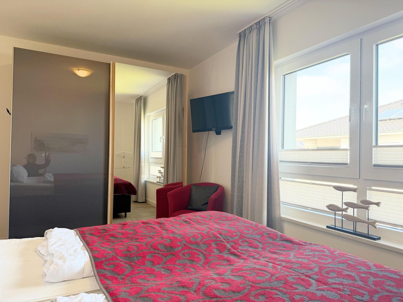 Schlafzimmer mit Bett, Fernseher und Fenster mit Blick.