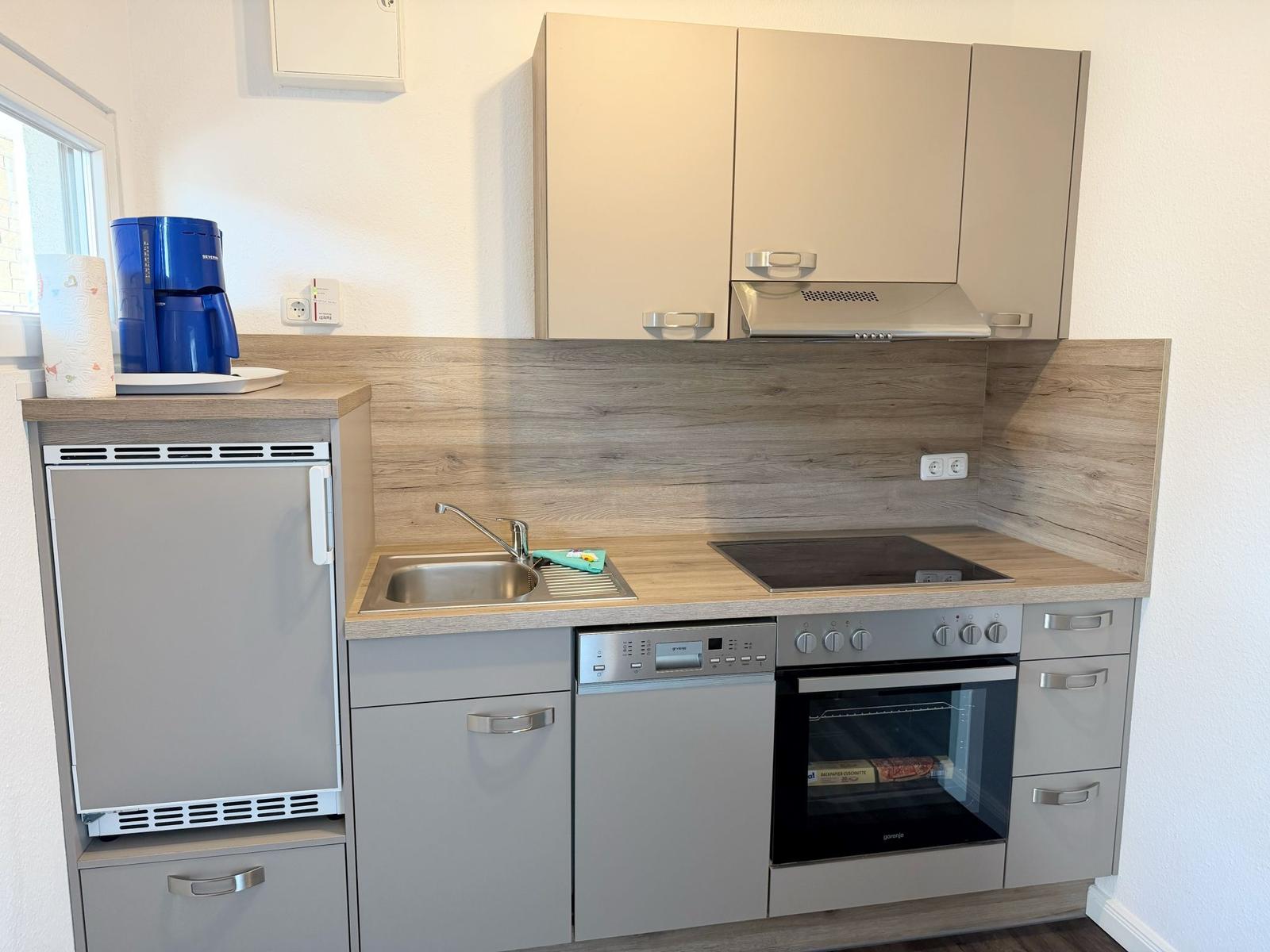 Küche mit Kühlschrank, Spüle, Herd und Backofen.