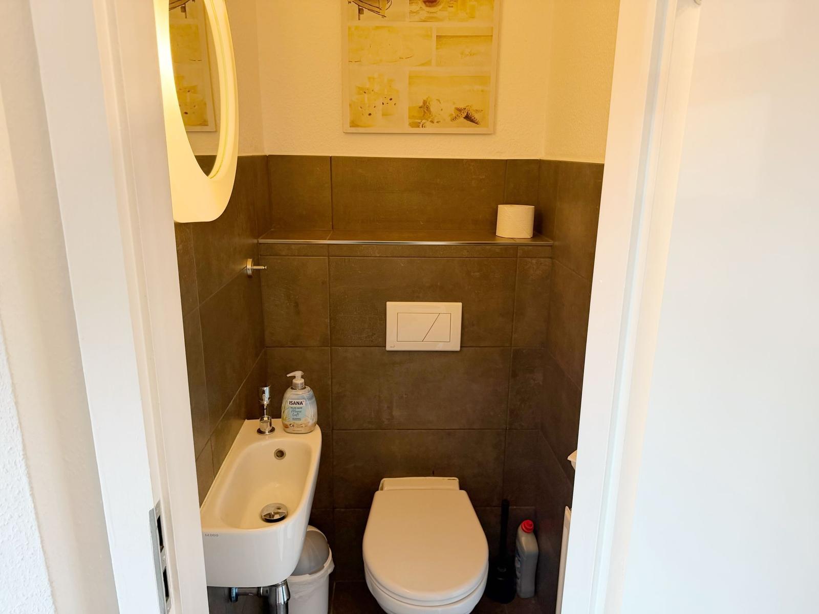Badezimmer mit Toilette, Waschbecken und Spiegel