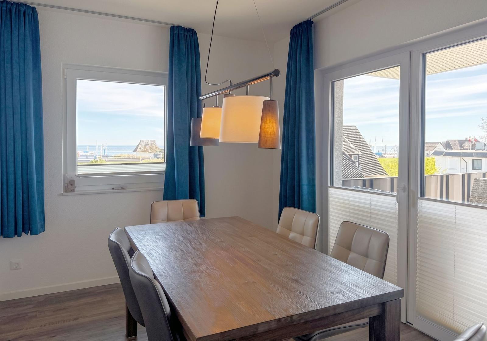 Esszimmer mit Holztisch, Stühlen und Blick aufs Meer.