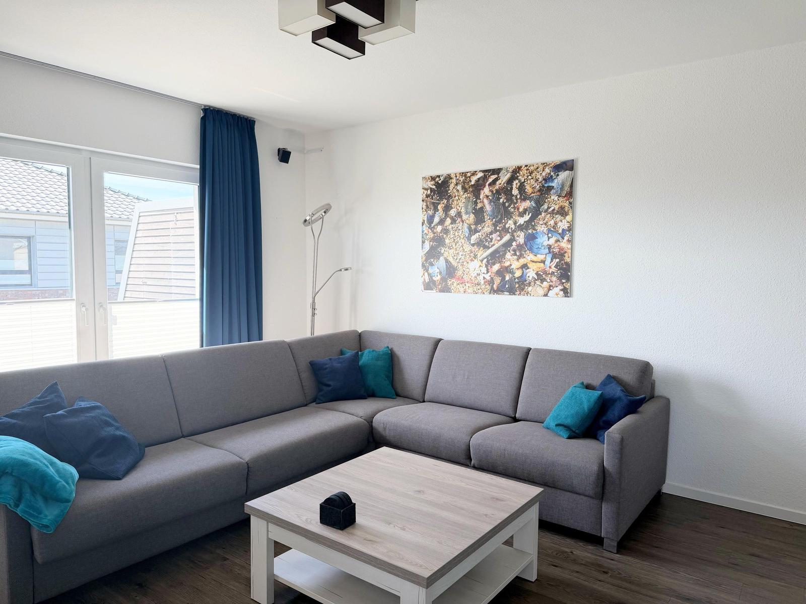 Ein Wohnzimmer mit grauem Sofa, blauen Kissen und einem Holztisch.