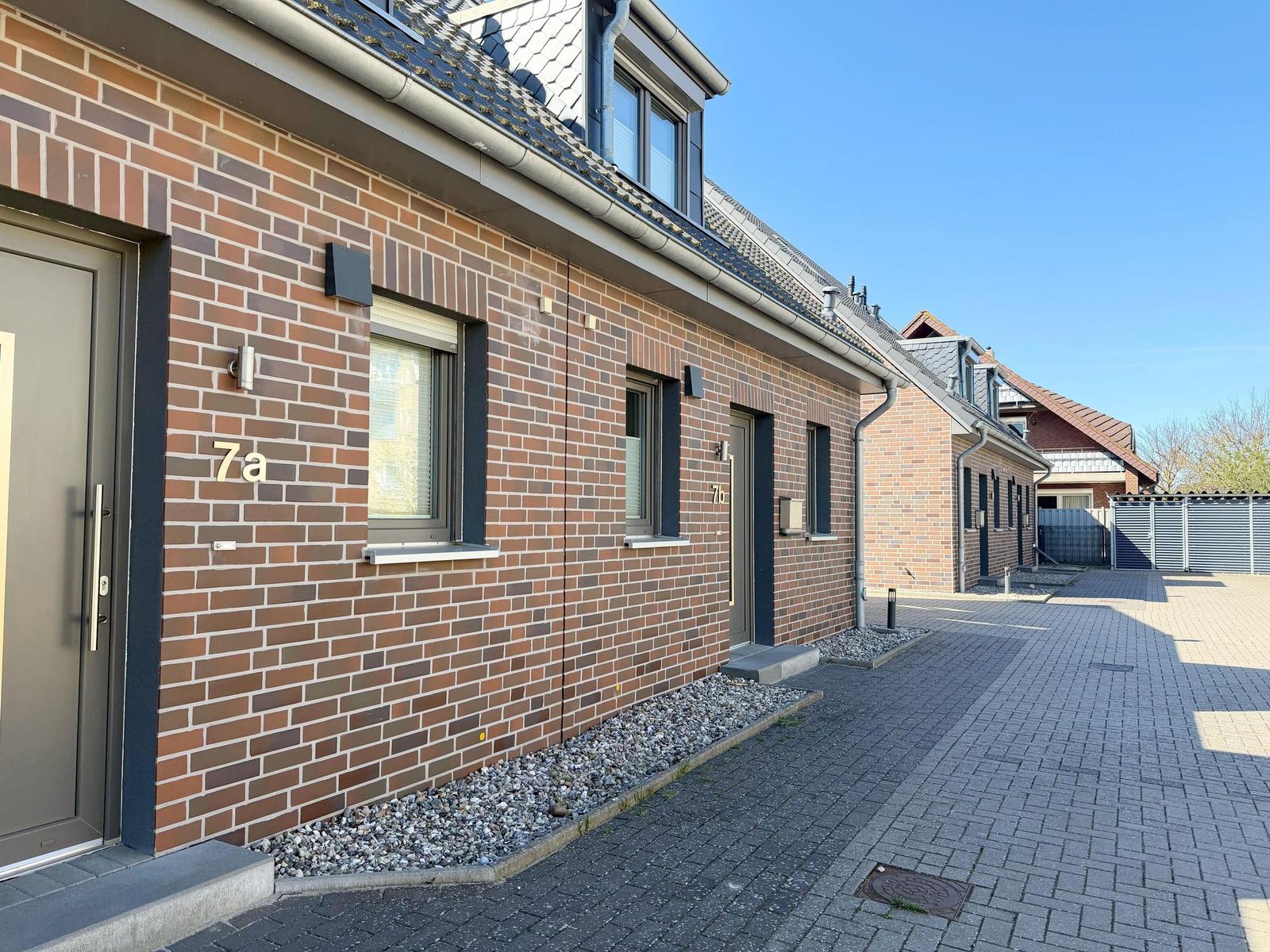 Ferienwohnung mit Zufahrt und Terrasse, modernes Gebäude mit Ziegelmauerwerk.