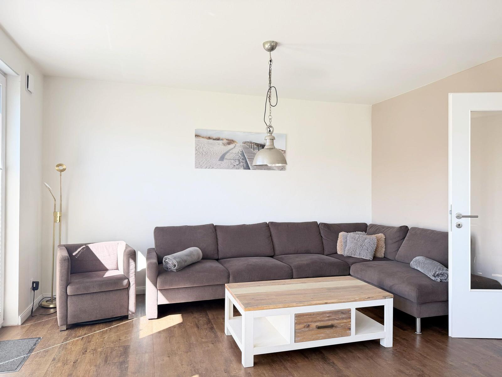 Wohnzimmer mit grauem Sofa, Holztisch und Wandbild.
