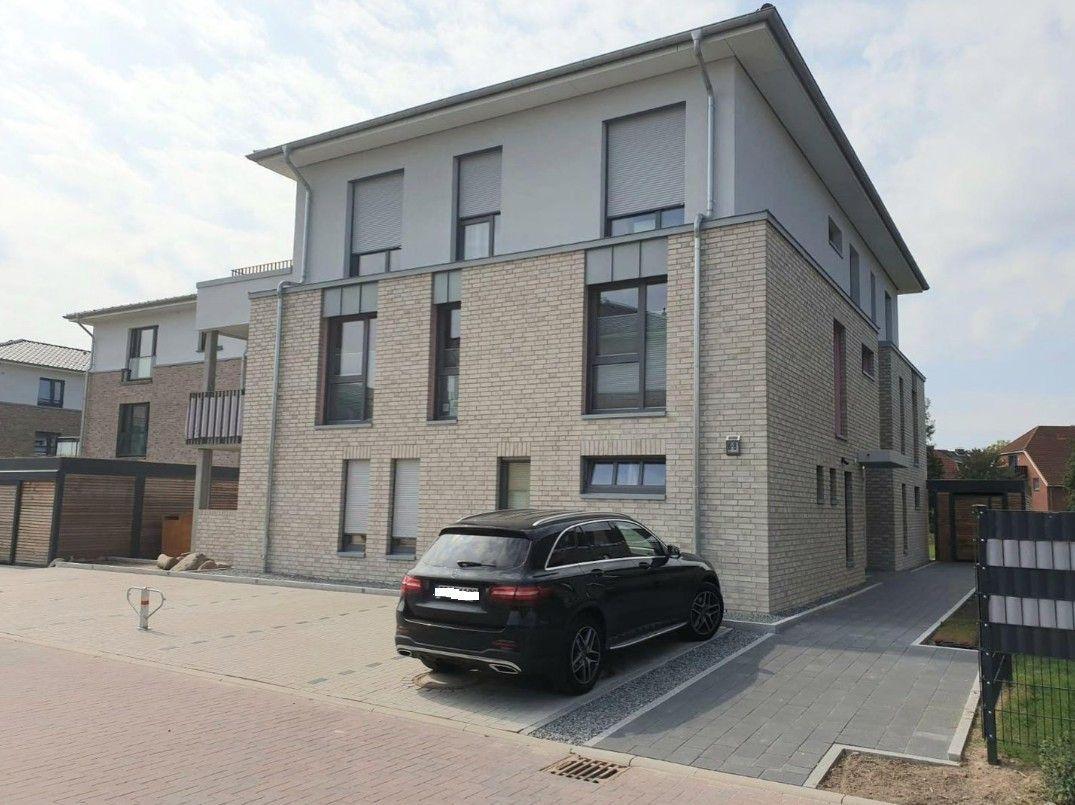 Moderne zweistöckige Villa mit gepflastertem Hof und parkendem Auto.