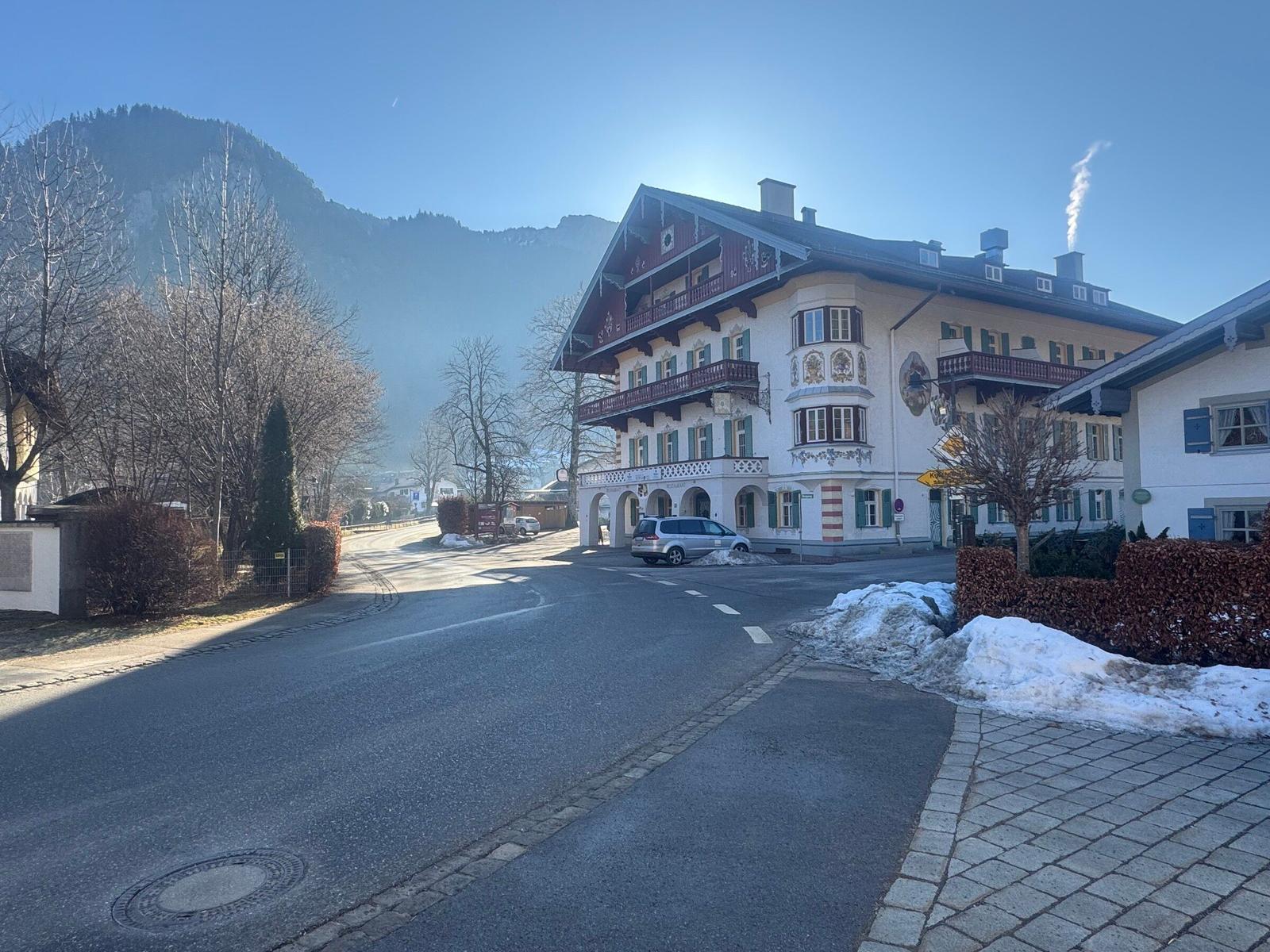 Traditionelles Haus mit Balkonen und Schnee am Straßenrand.