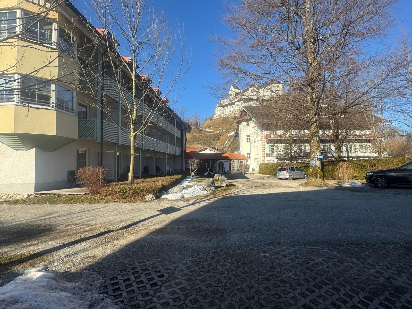 Vor dem Haus mit Blick auf Schloss und Parkplatz mit Autos.
