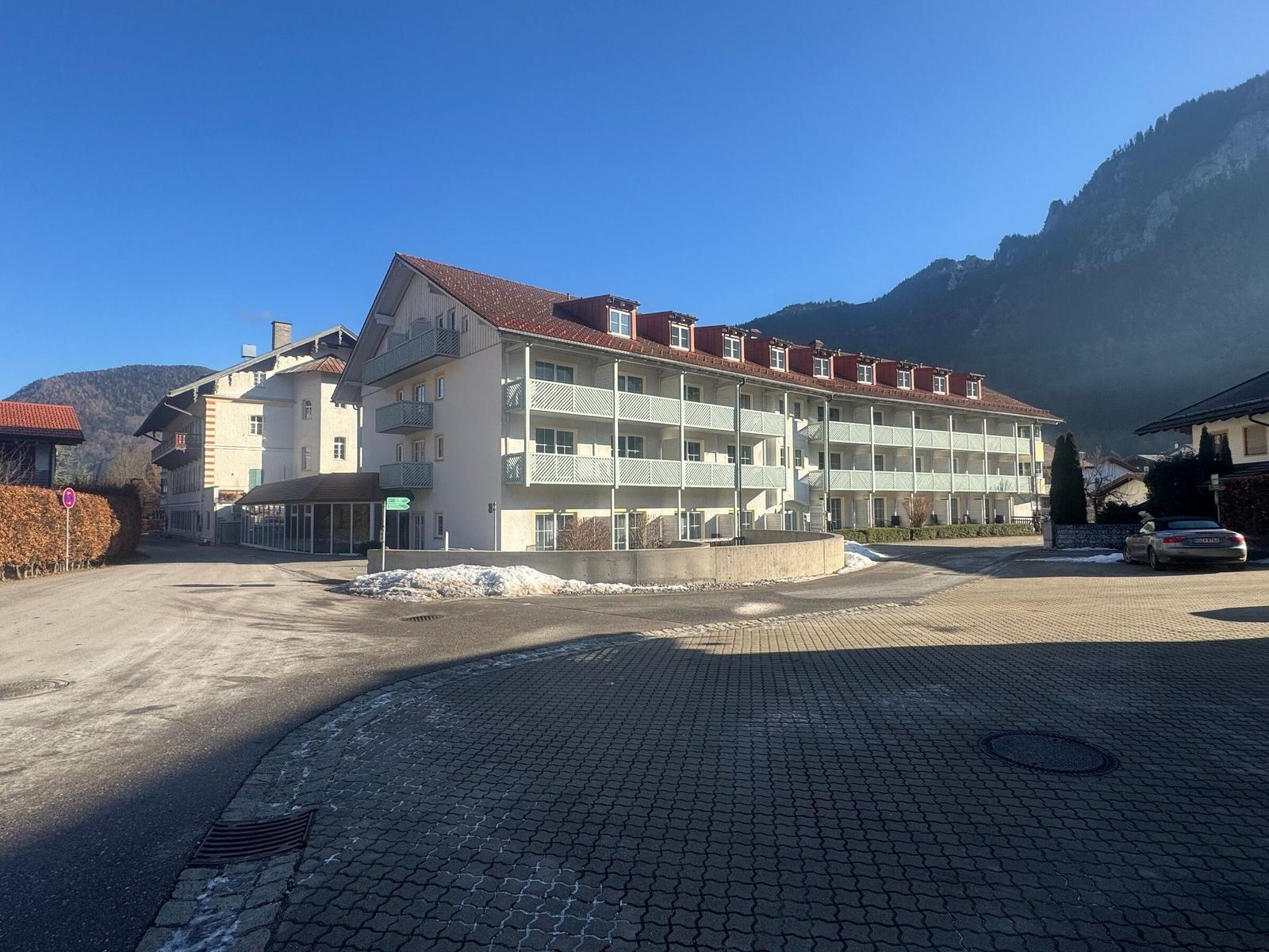Ferienhaus mit Balkonen und rotem Dach vor Berglandschaft.