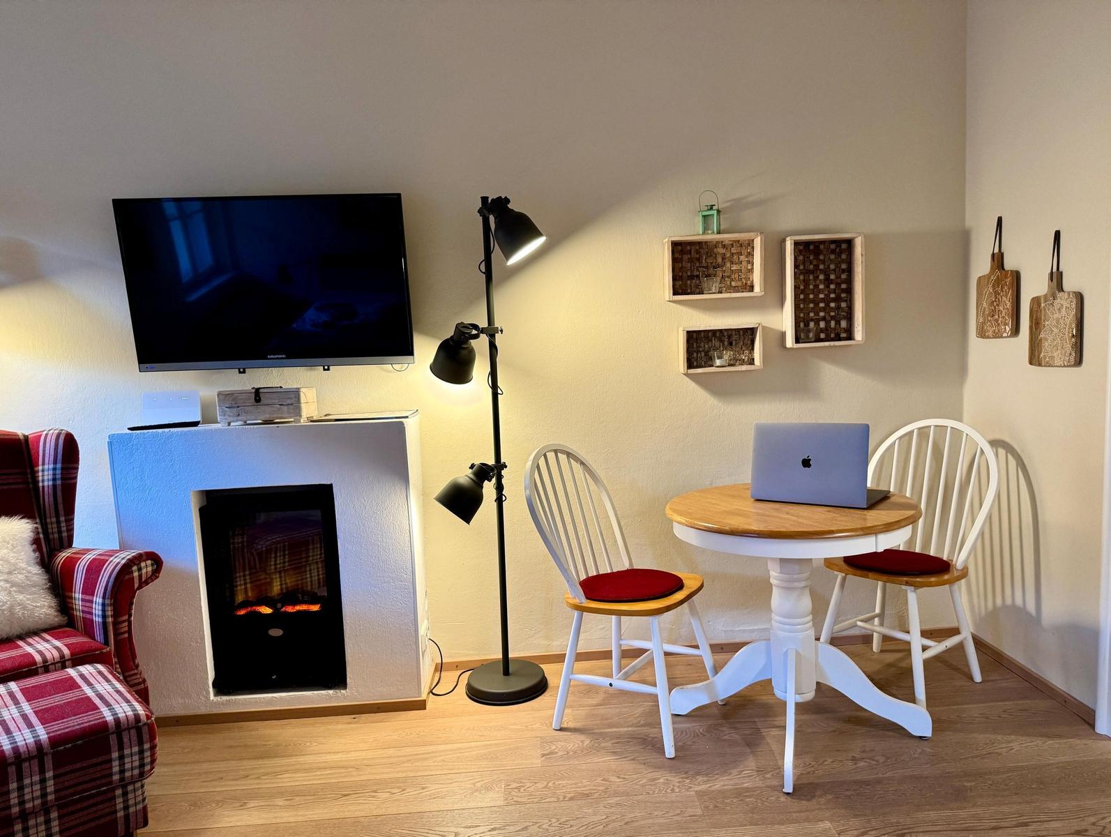 Raum mit Fernseher, Kamin und Esstisch mit zwei Stühlen.