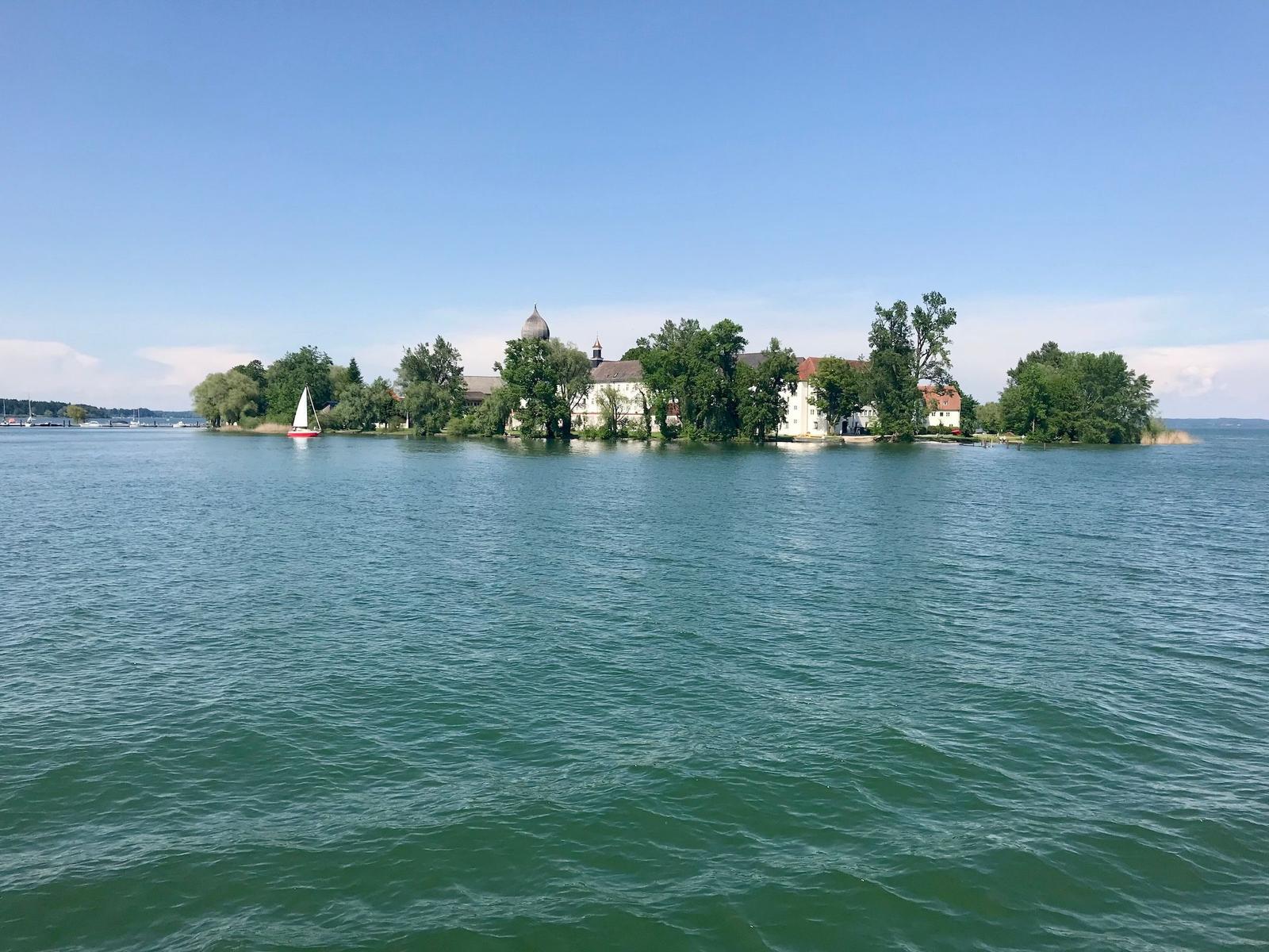 Schlossinsel mit Segelboot auf dem See unter blauem Himmel