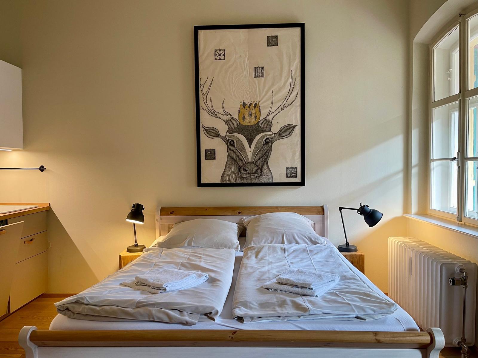 Schlafzimmer mit Doppelbett, Wandbild und Fenster.