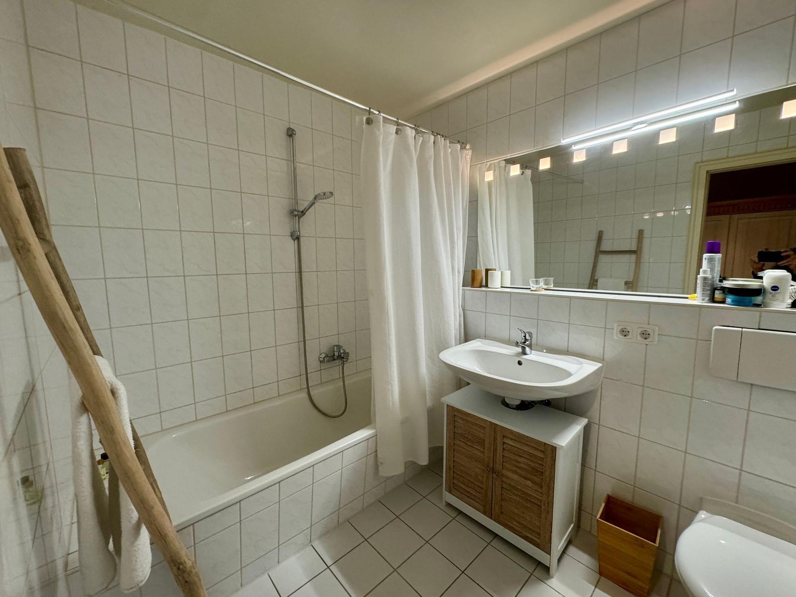 Badezimmer mit Badewanne, Dusche, Waschbecken und Spiegel.