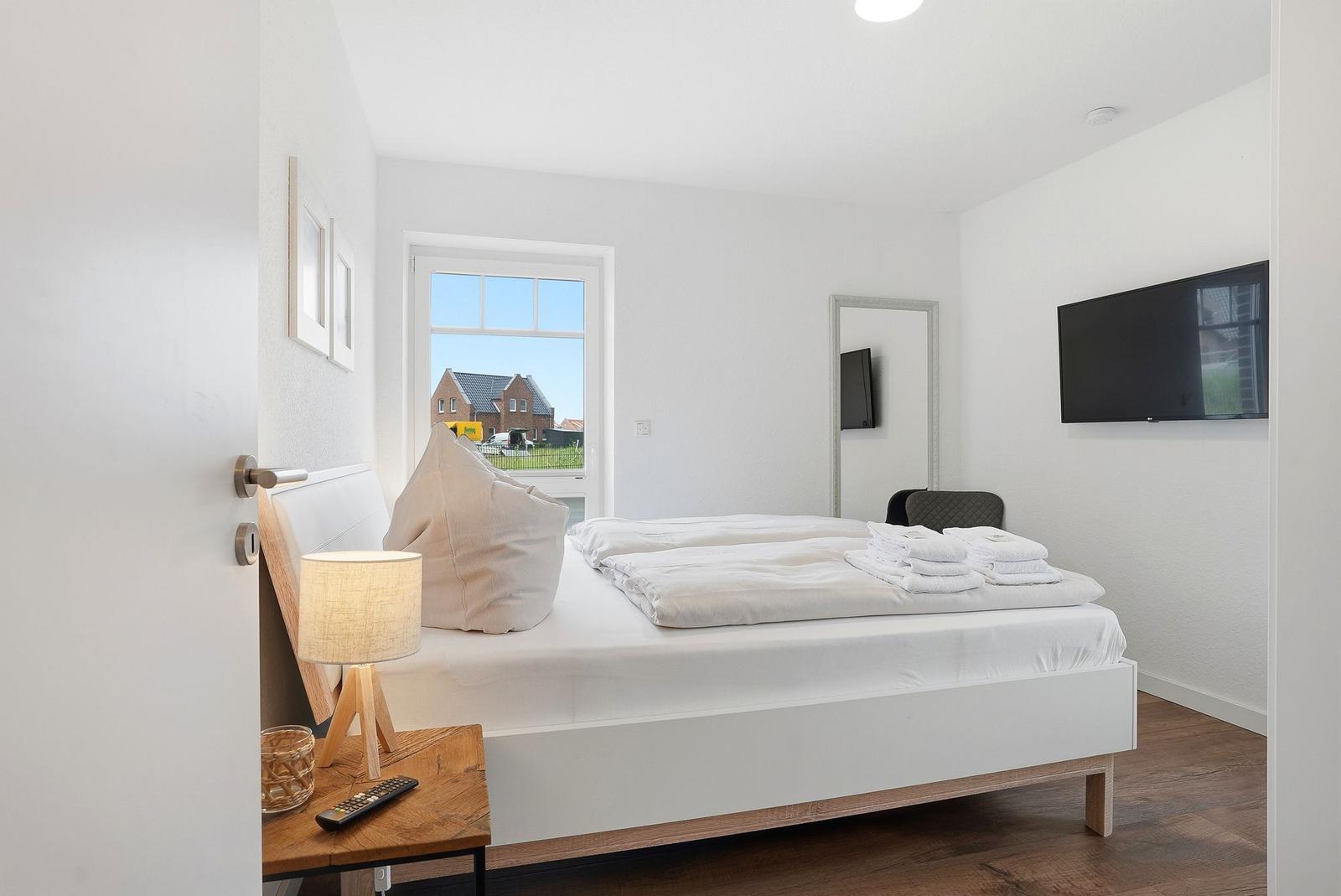 Schlafzimmer mit Bett, Fernseher und Fenster zum Garten