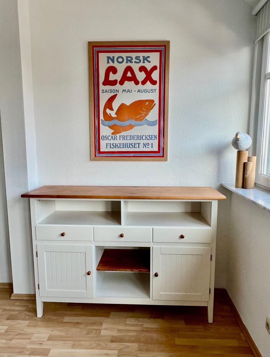 Weißer Sideboard mit Holzoberfläche unter einem Fischposter an der Wand.