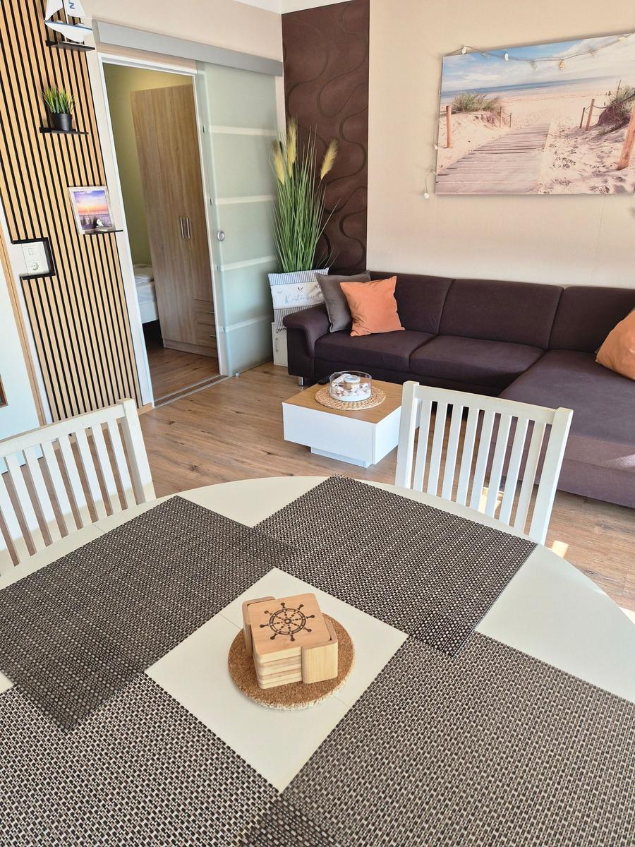 Essbereich mit Tisch und Stühlen, Wohnbereich mit Sofa und Wandbild.
