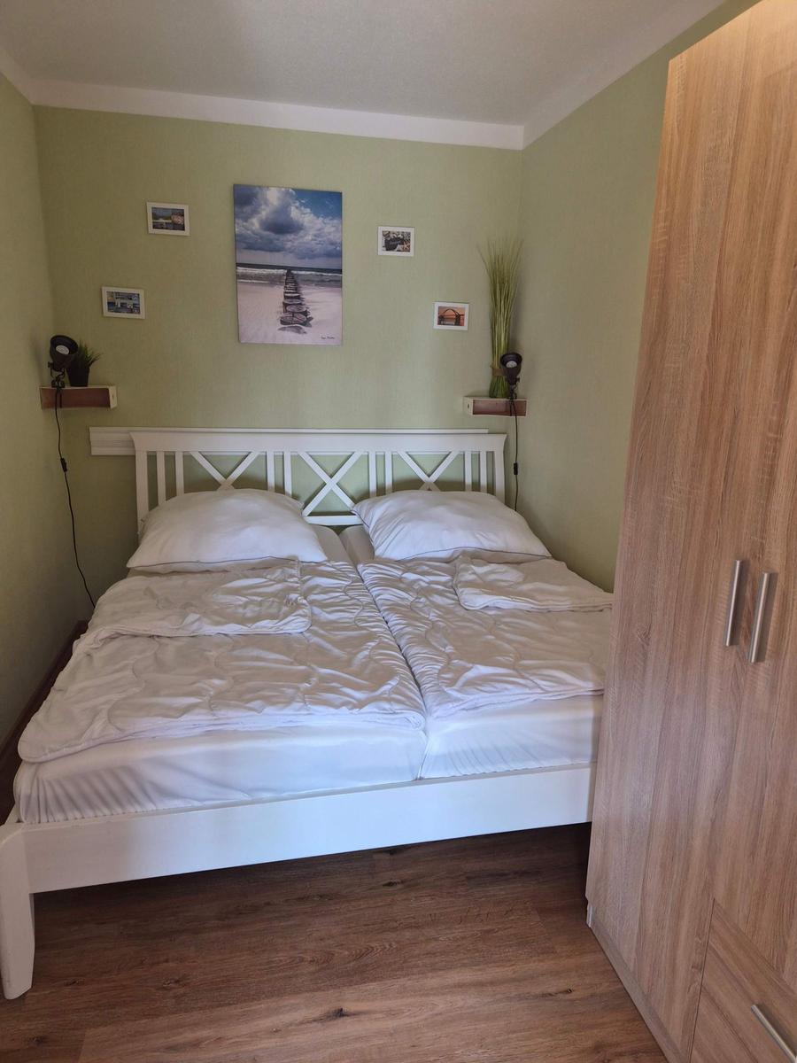 Schlafzimmer mit Doppelbett, Holzschrank und Wandbildern.