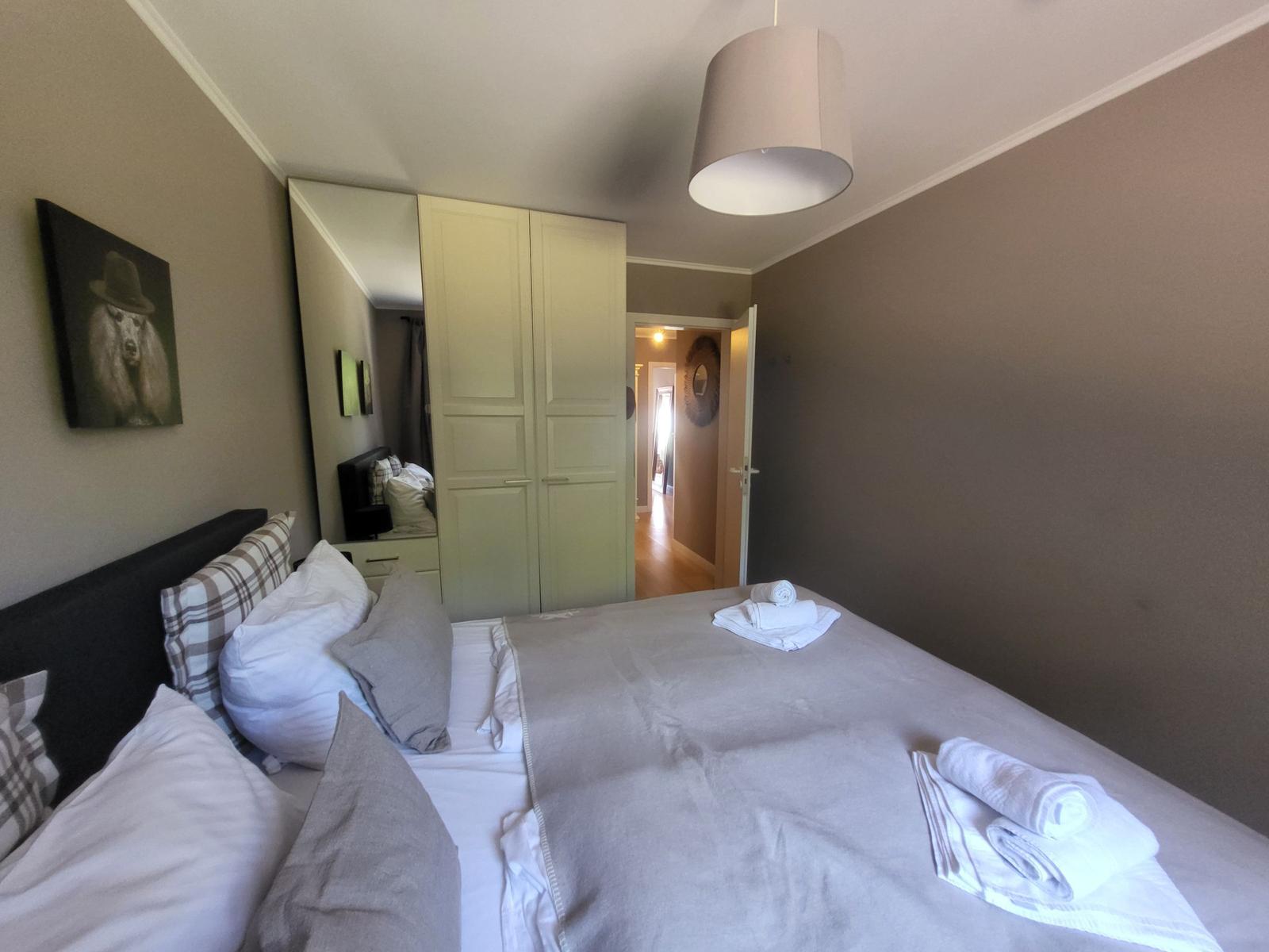 Schlafzimmer mit Bett, Kleiderschrank und Decke. An der Wand hängt ein Bild.