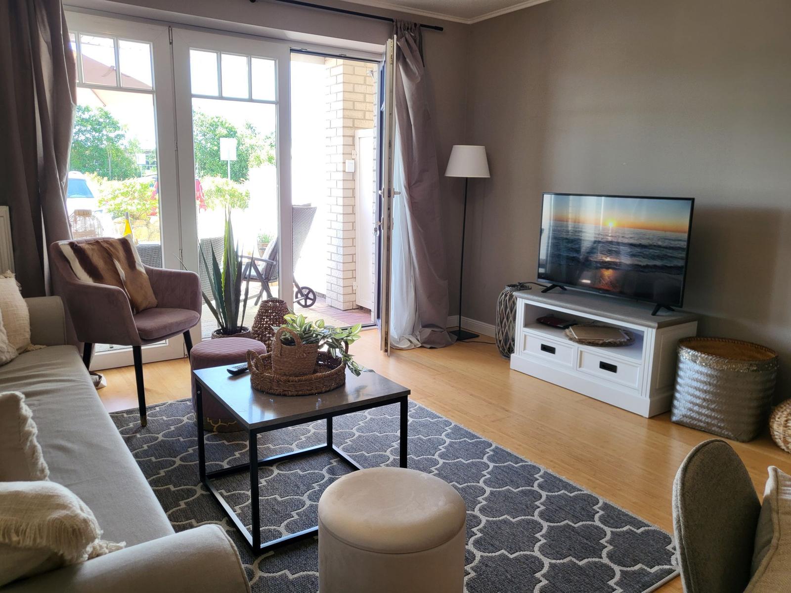 Wohnzimmer mit Sofa, Fernseher und Terrassentür.