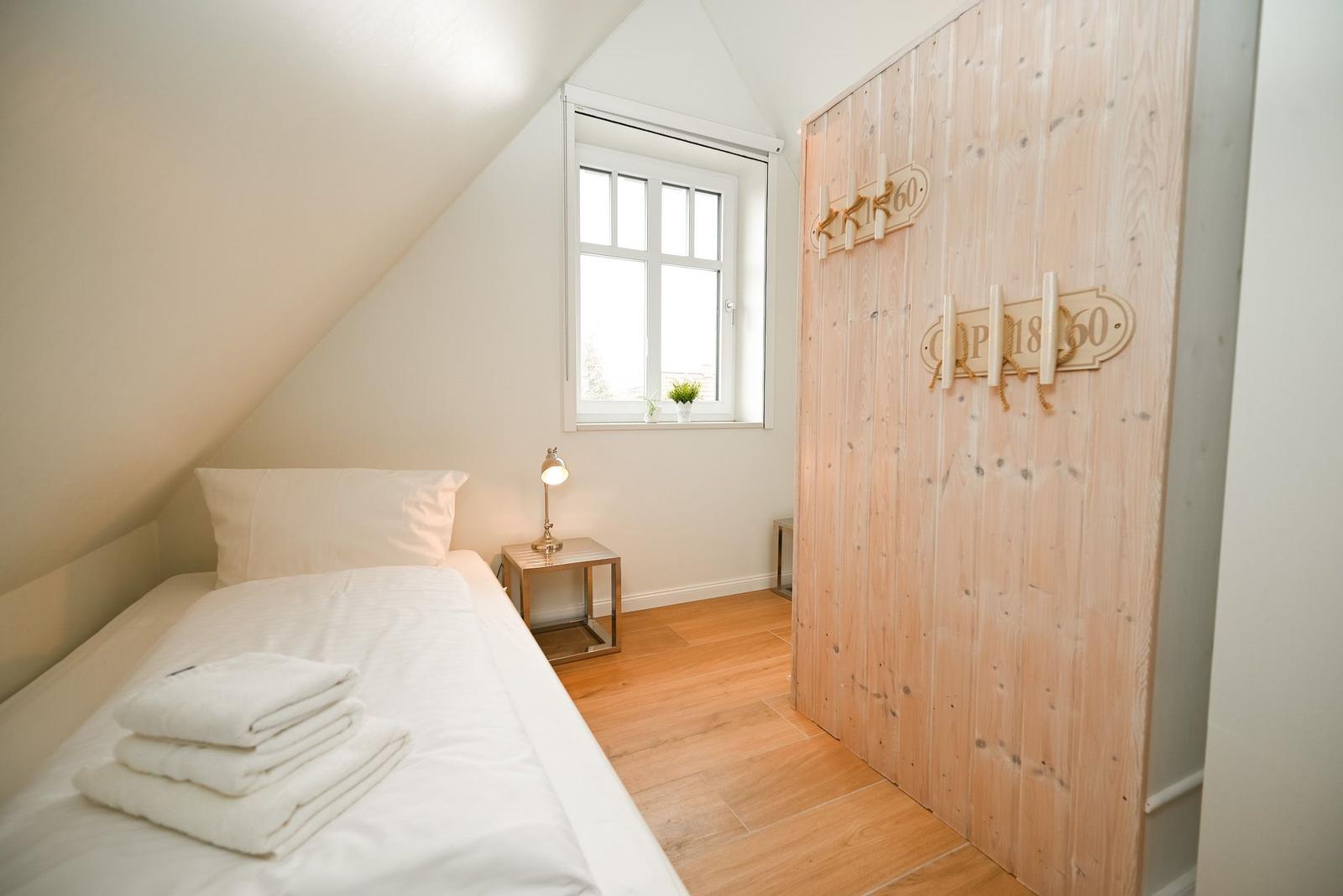 Ein Schlafzimmer mit Dachschrägen, Bett, Nachttisch und Holzwand.