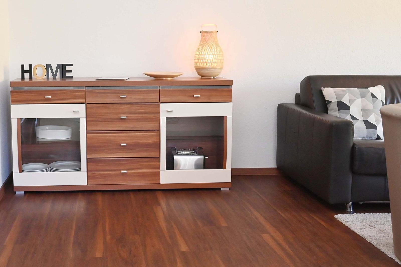 Moderne Wohnküche mit Holzoptik, Sofa und Beleuchtung.
