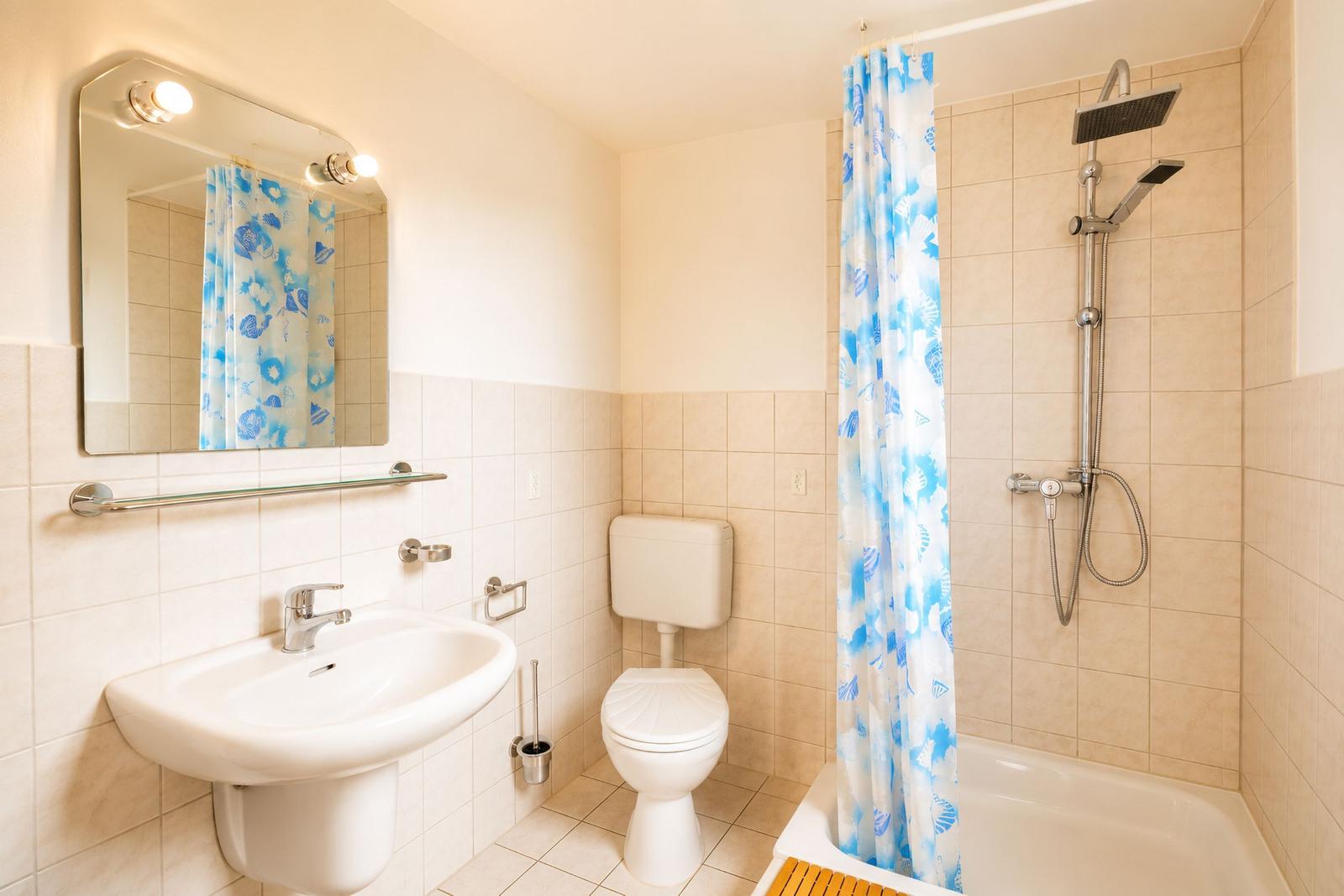 Badezimmer mit Dusche, Toilette und Waschbecken.