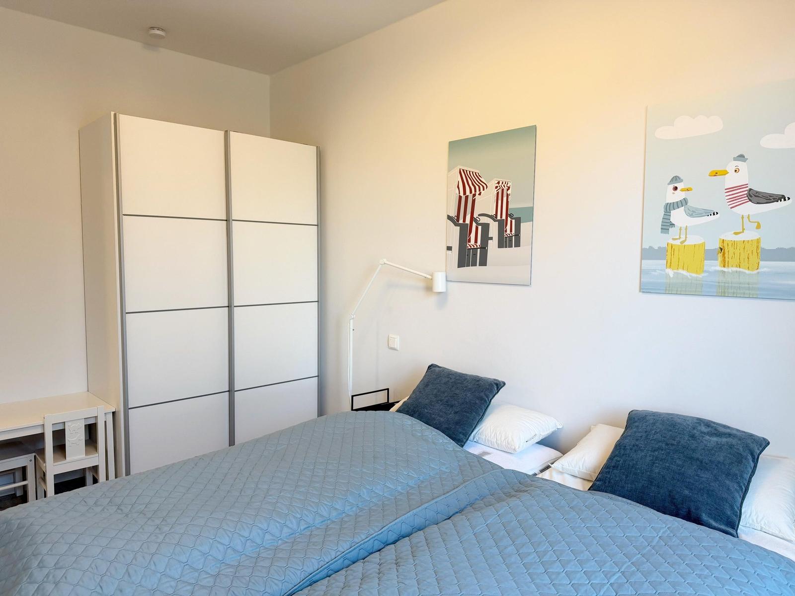 Schlafzimmer mit Doppelbett, Kleiderschrank und Wandbildern mit Möwenmotiven.