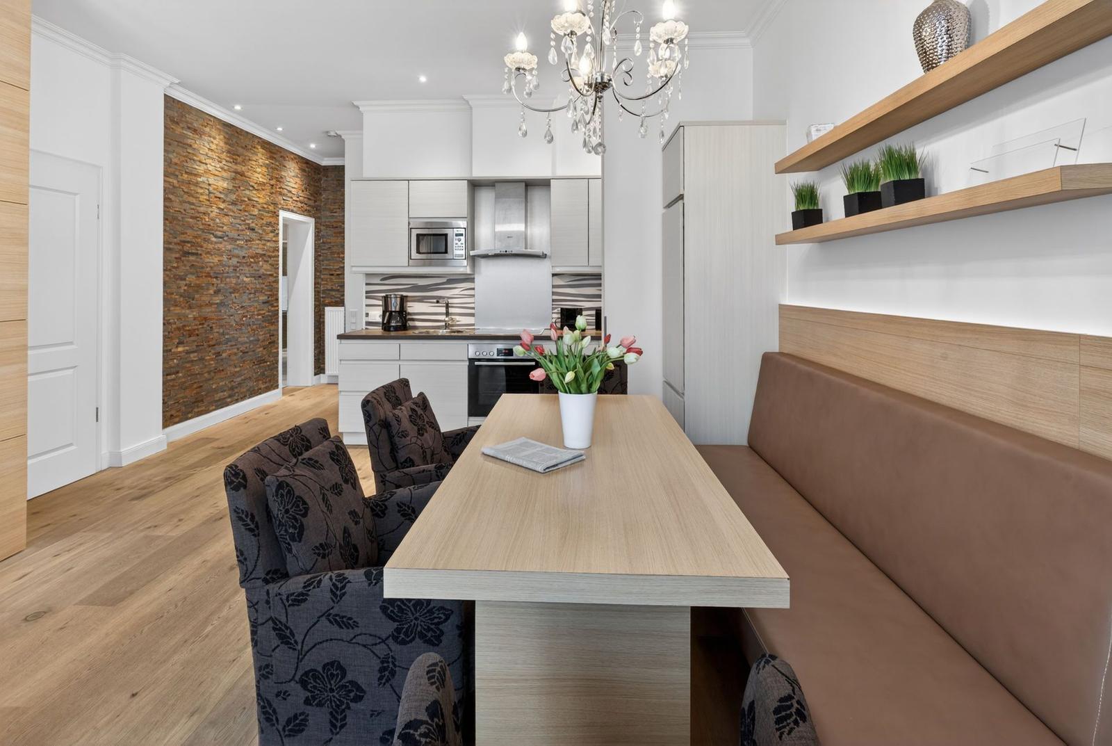 Essbereich mit Holztisch, Sitzbank und Küchenbereich im Hintergrund.