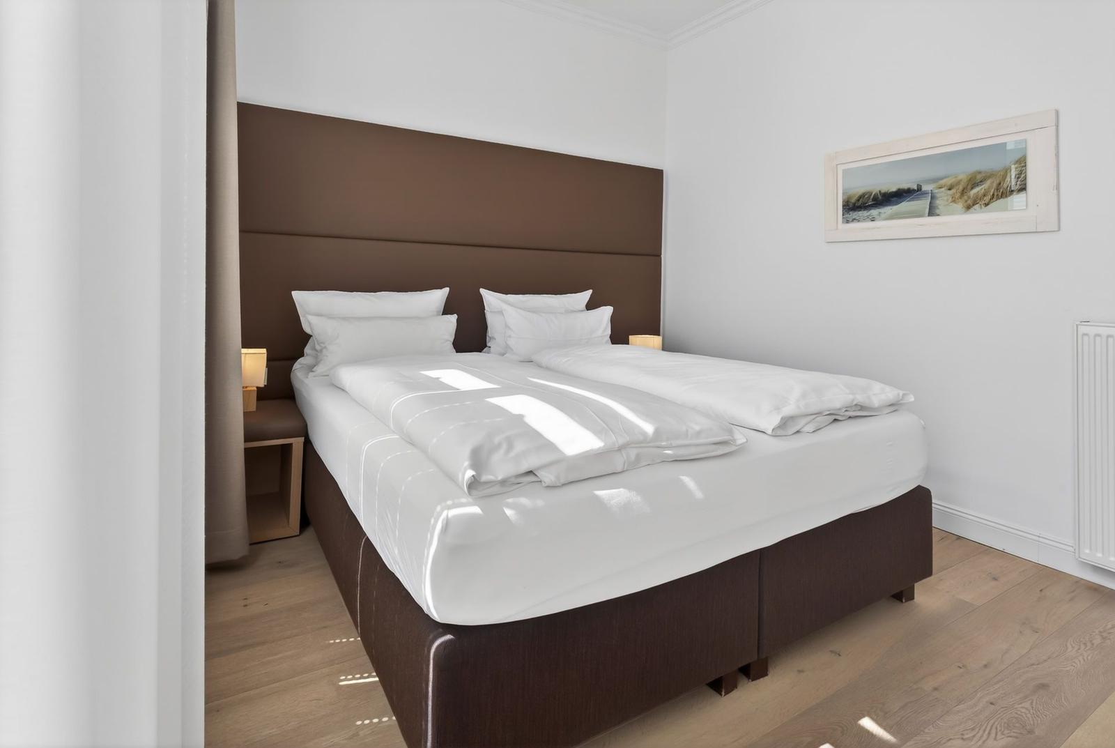 Schlafzimmer mit Bett, Kopfteil und Wandbild.