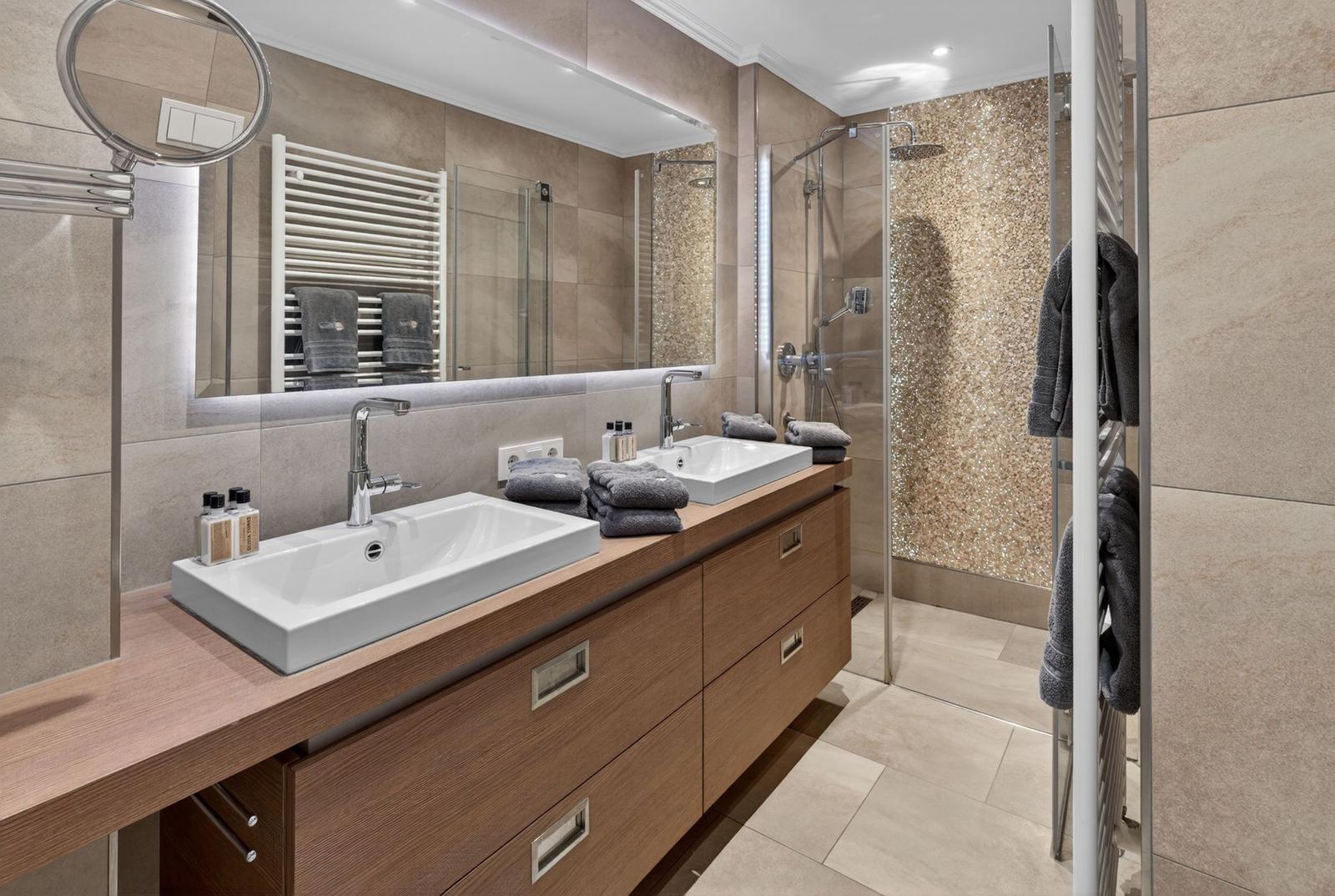 Badezimmer mit Doppelwaschbecken, Dusche und Heizkörper