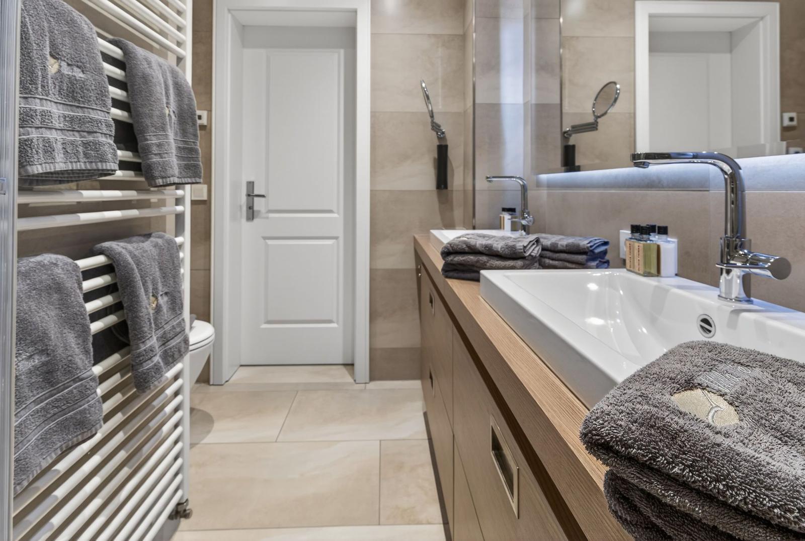 Badezimmer mit Waschbecken, Handtuchheizkörper und Spiegel