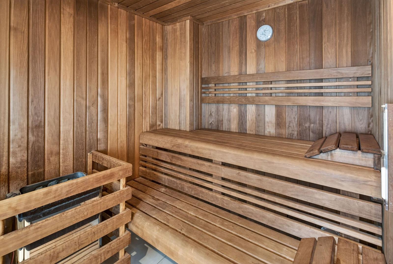 Sauna mit Holzbank und Temperaturmessgerät an der Wand.