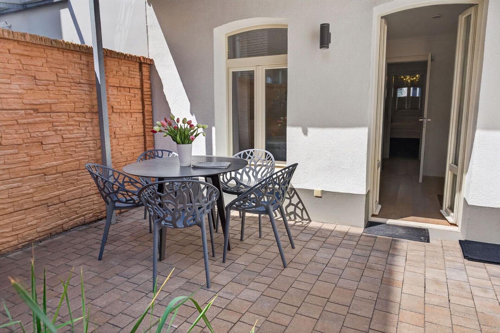 Terrasse mit Tisch und Stühlen, Pflanzen und Blick in das Haus.