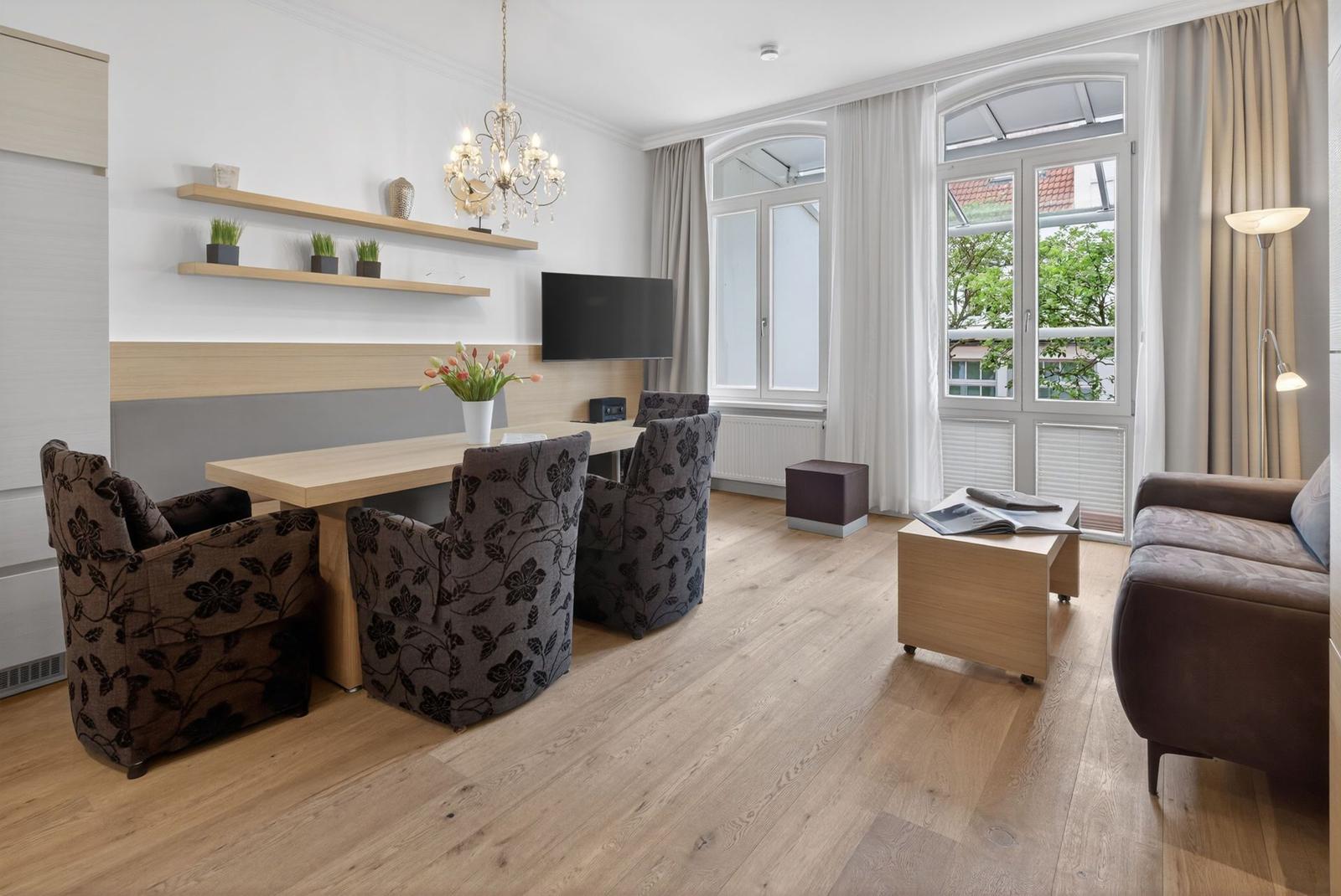 Wohn- und Essbereich mit Holzboden, Fenster und Möbeln.