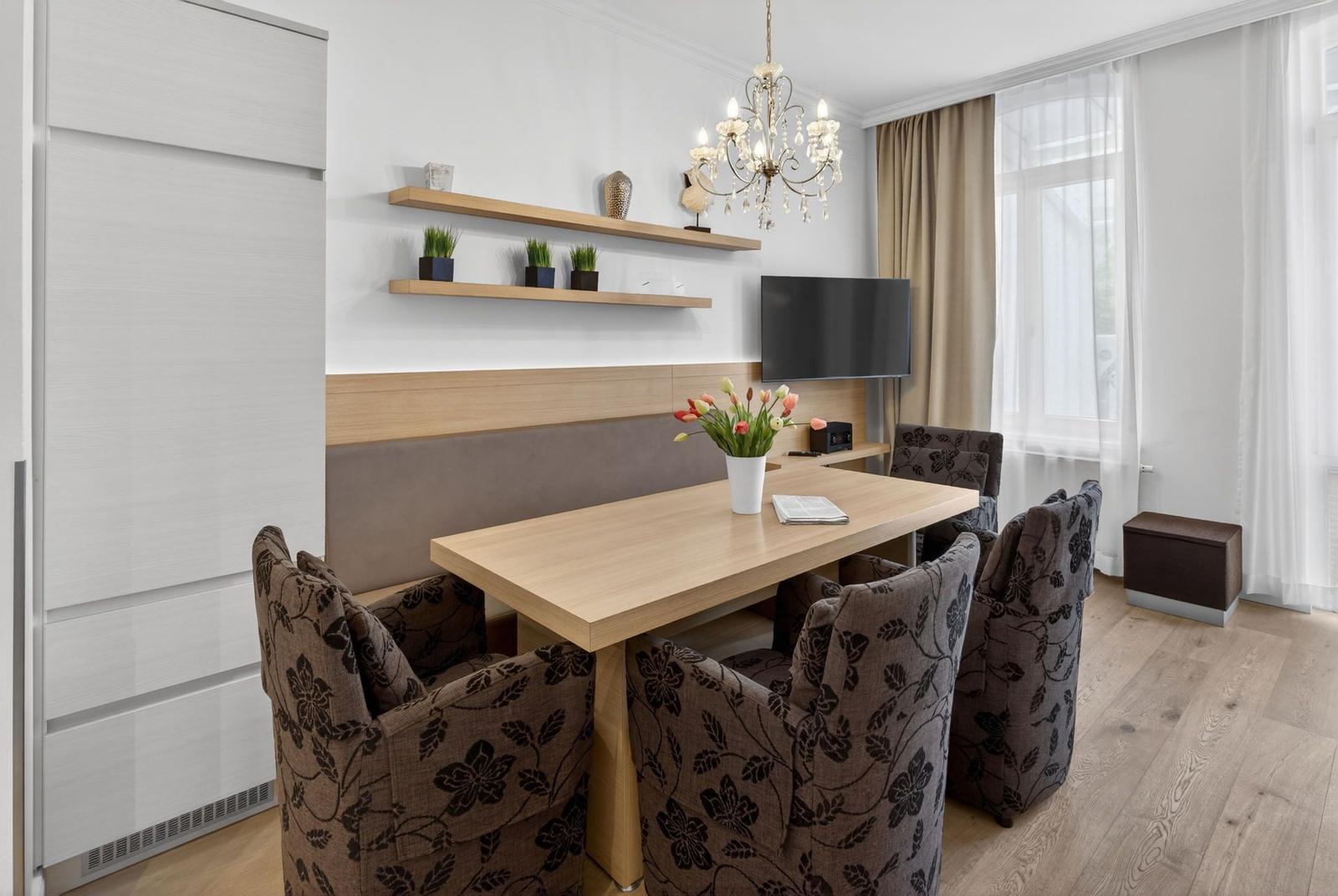 Essbereich mit Tisch, Stühlen und Fernseher an der Wand.