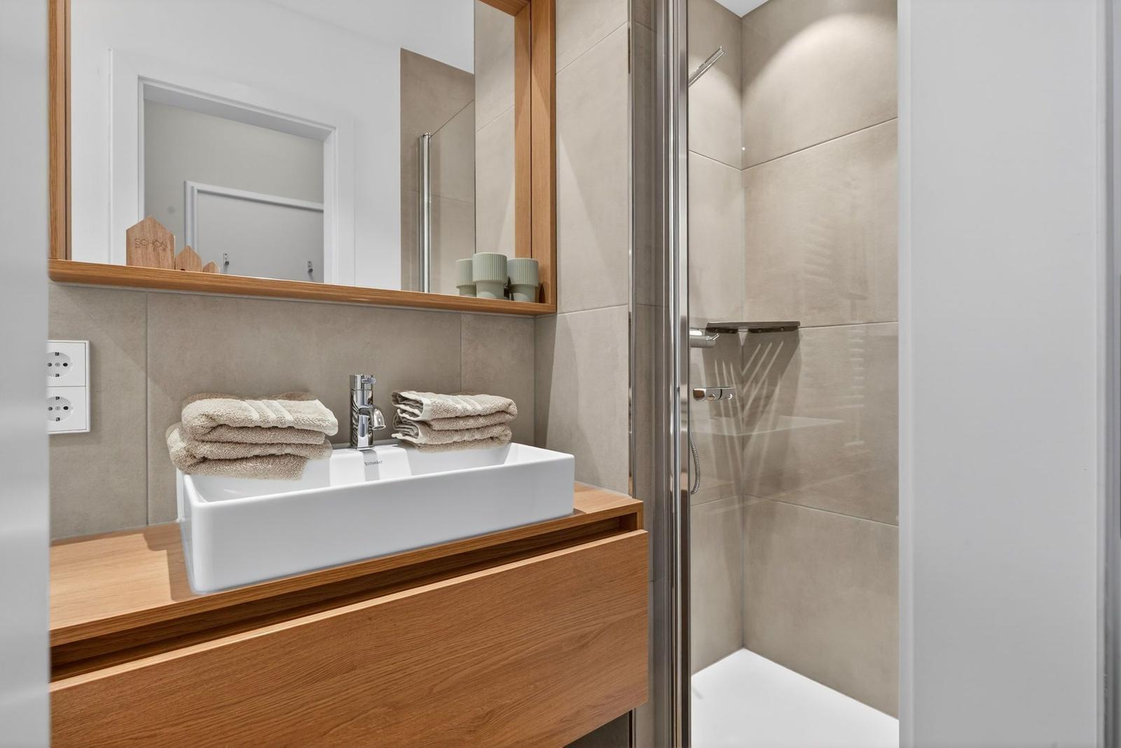 Badezimmer mit Waschbecken, Spiegel und Dusche.
